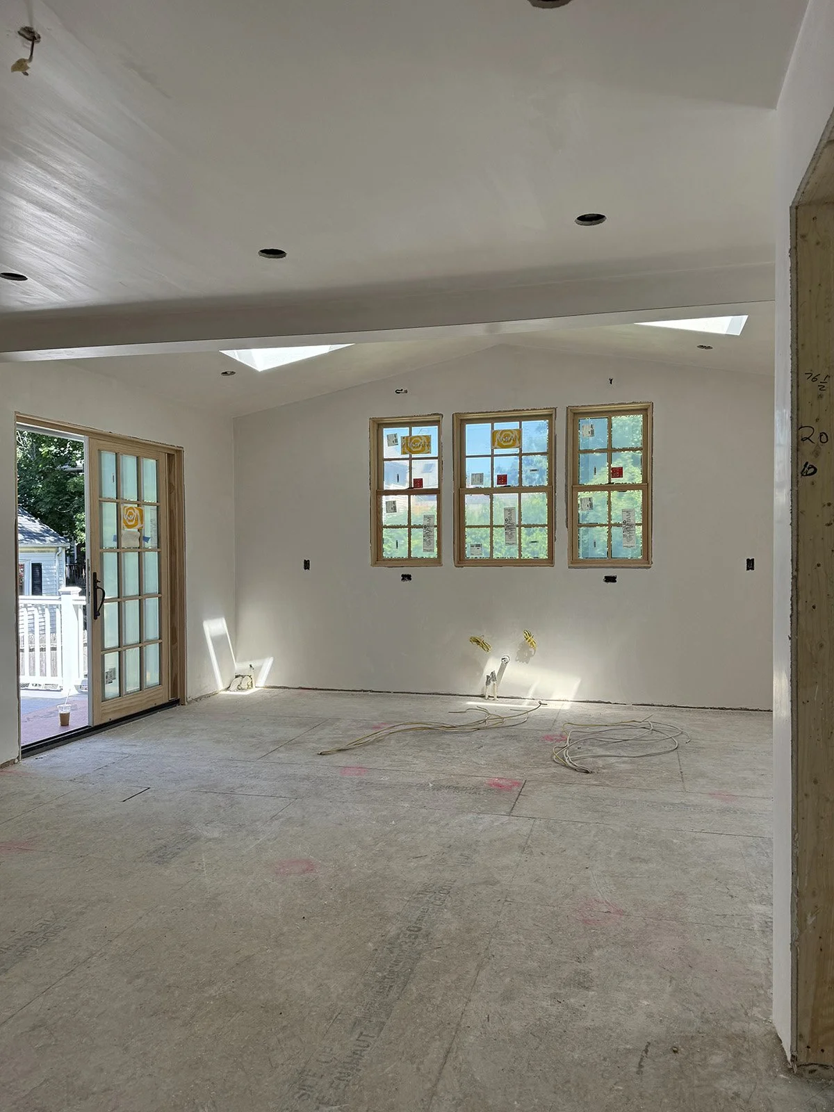 Board and plaster phase of construction in a Dutch colonial home in Medford, MA showing open door to new deck