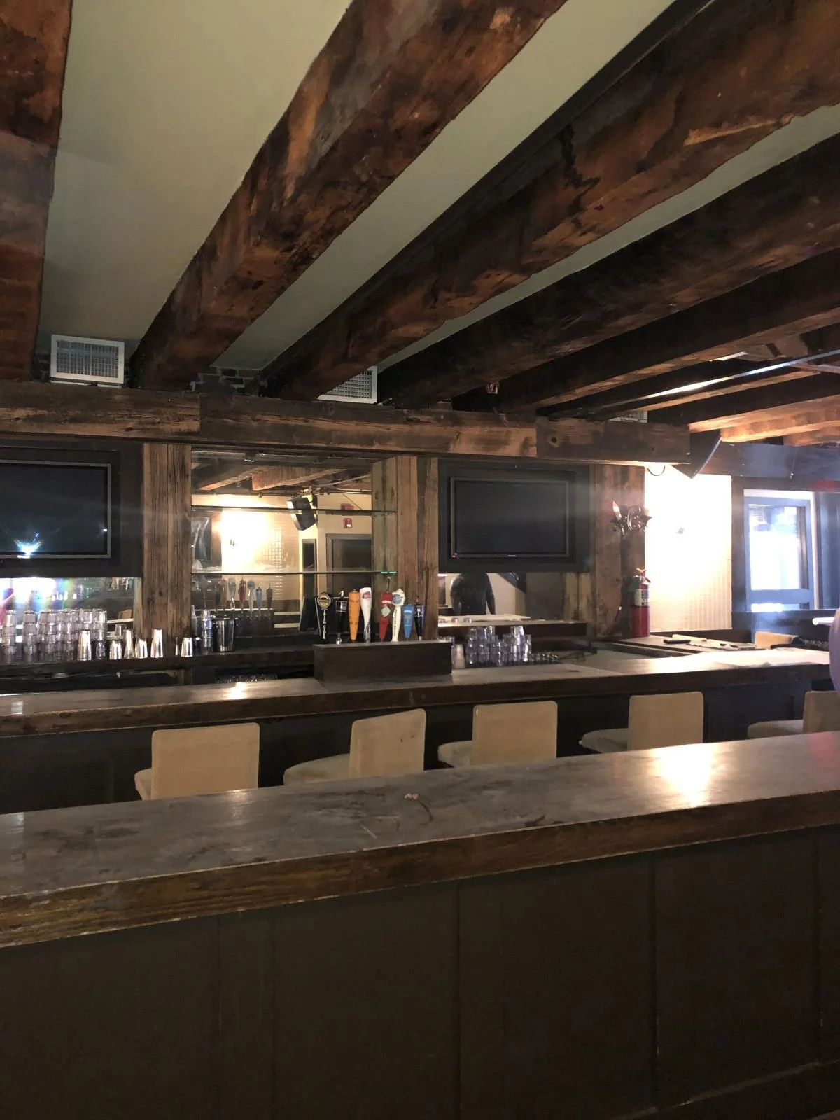 A ground-level bar with exposed wood beams and taps, prior to renovation.
