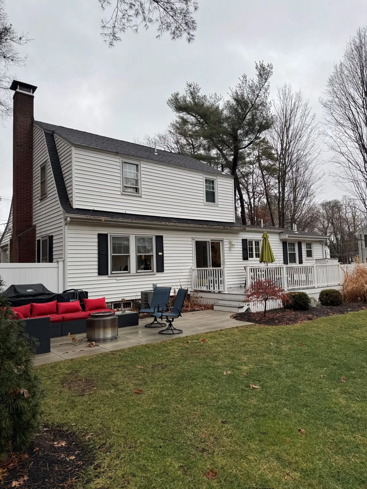 Existing rear exterior of a Dutch Colonial home in Greater Boston prior to second story addition showing original one story addition and rear facade before renovation by Tact and Grit Design Co.