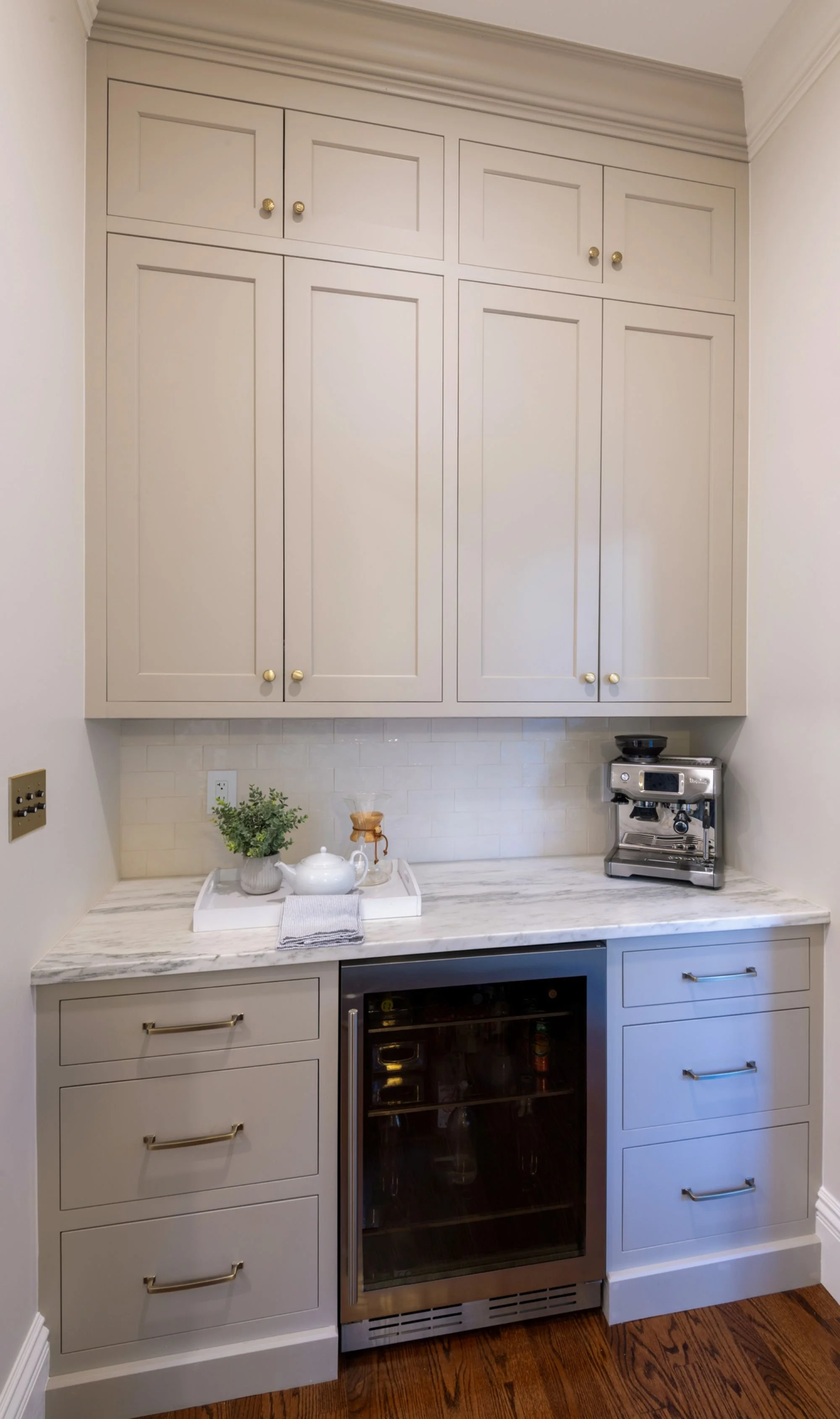 Renovated breakfast nook coffee bar cabinetry in an 1846 Victorian home in Newton MA featuring custom floor to ceiling inset cabinetry with marble countertop and beverage refrigerator