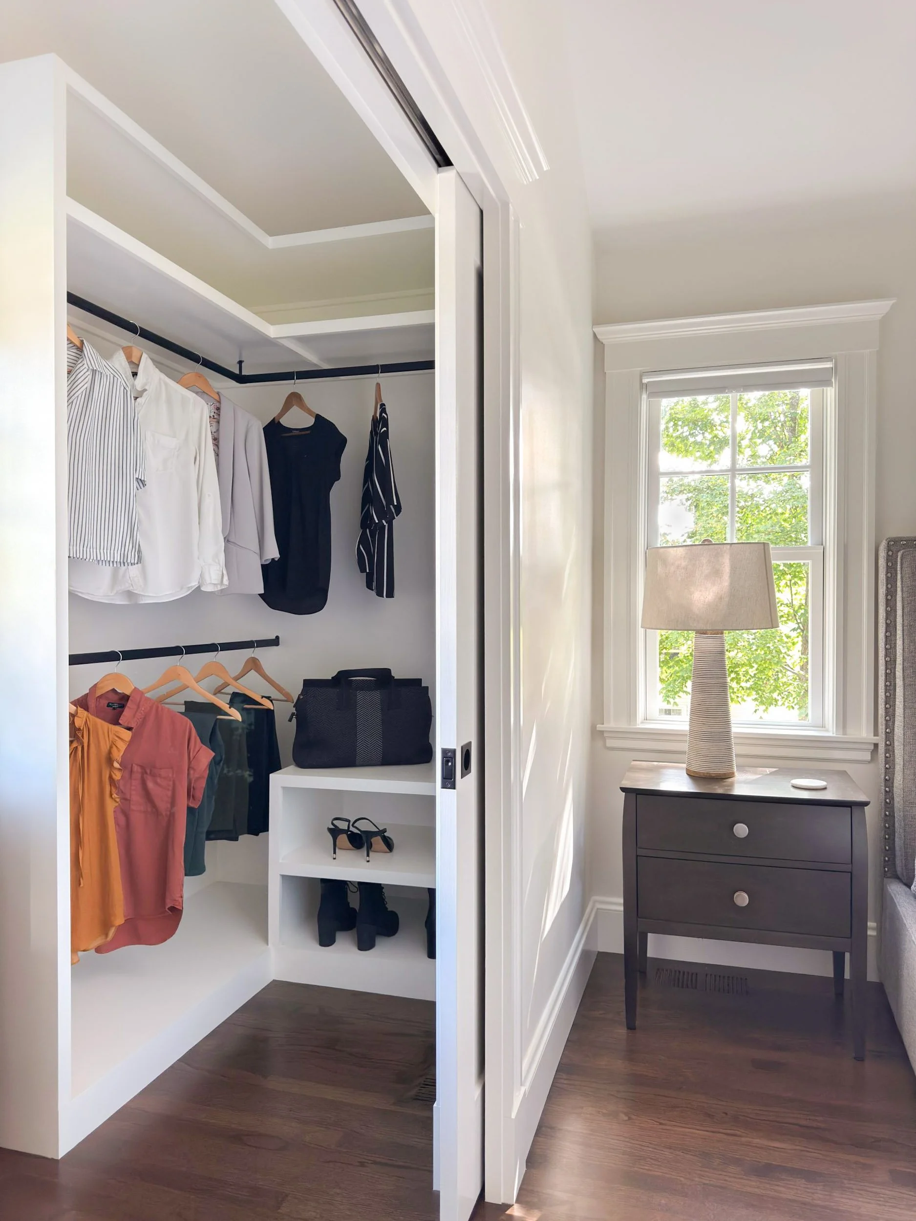 Her side of a his and hers walk-in closet in a Dutch Colonial primary suite addition in Greater Boston showing custom built-in shelving and hanging rods.