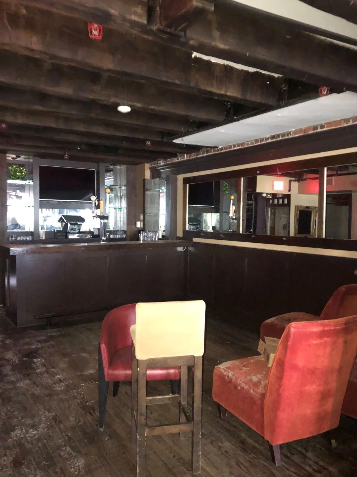 A second-level bar with red upholstered seating and a mounted television.
