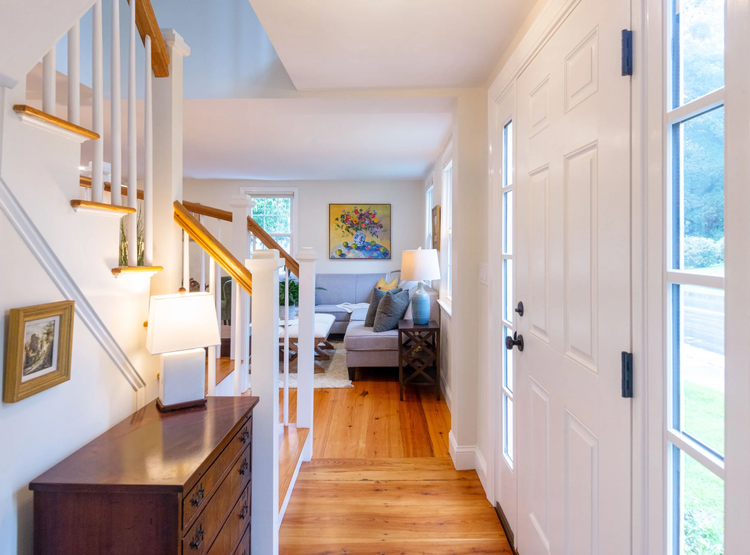A front entry with staircase and antique dresser, opening toward the living room