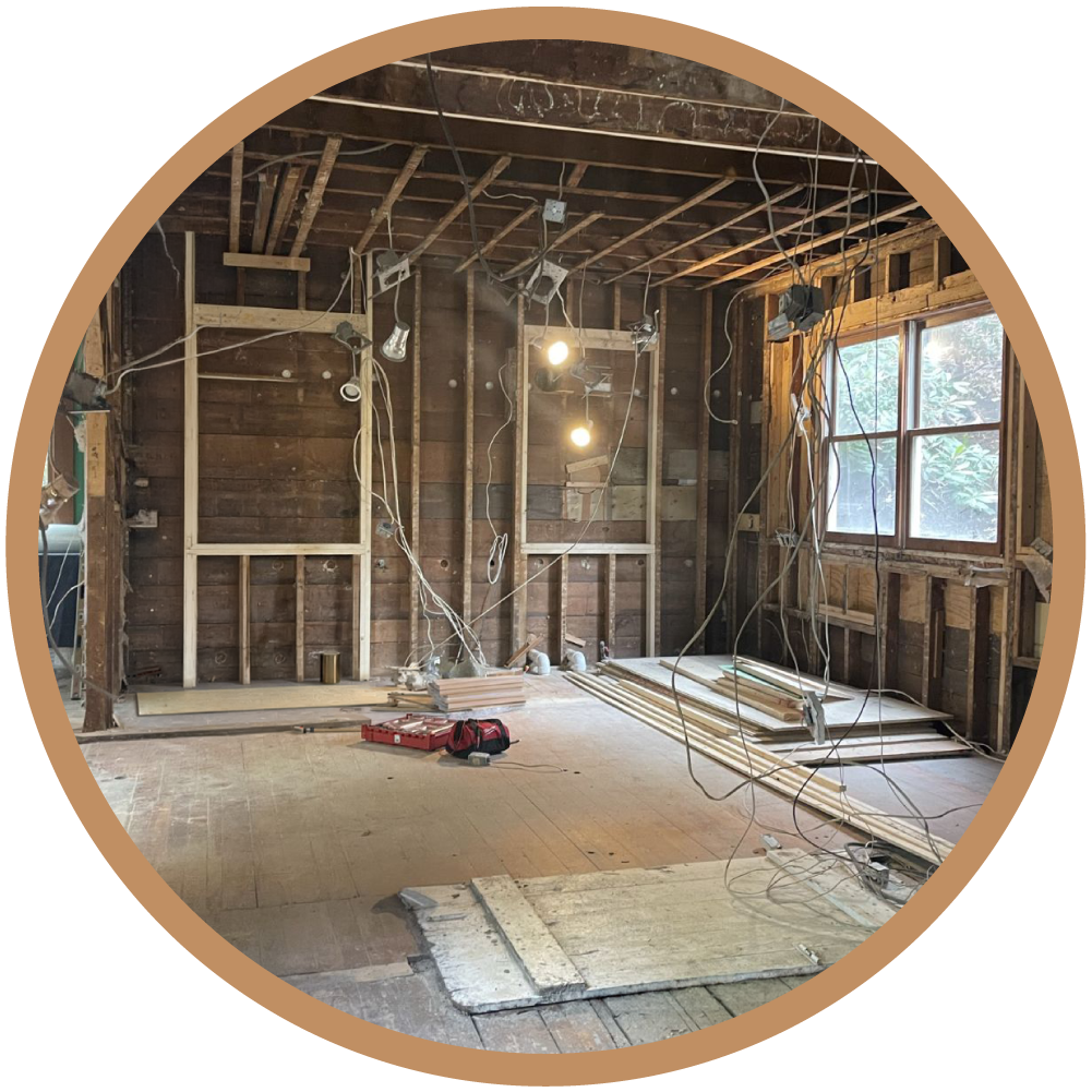 Interior view of the demolition phase in a historic home, showing exposed wall studs and the diagnostic screening of existing structural elements.