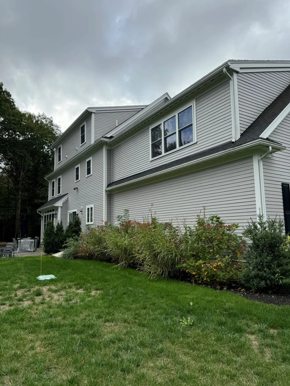 A side perspective showing an undifferentiated rear facade prior to additions and outdoor living in Hamilton, MA