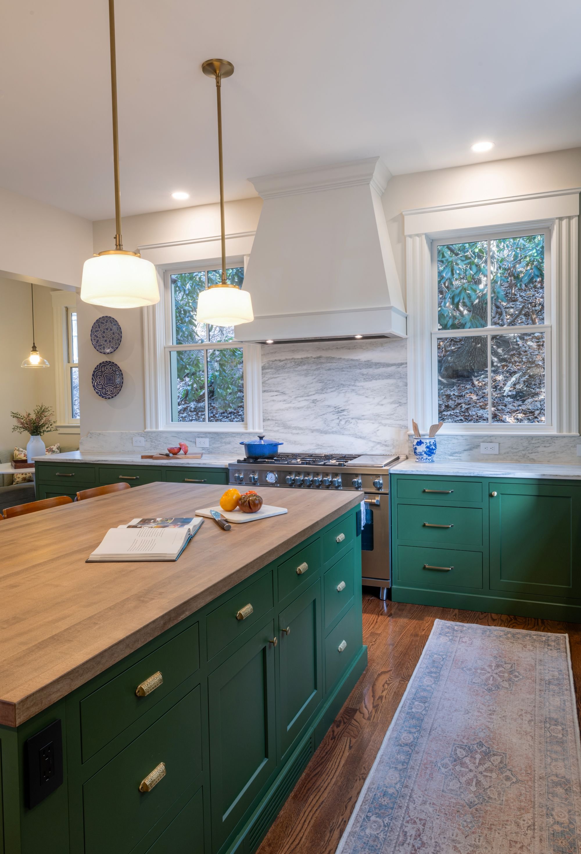Renovated kitchen in an 1846 Victorian home in Newton, MA showing working side of island with butcher block top viewed towards custom white range hood