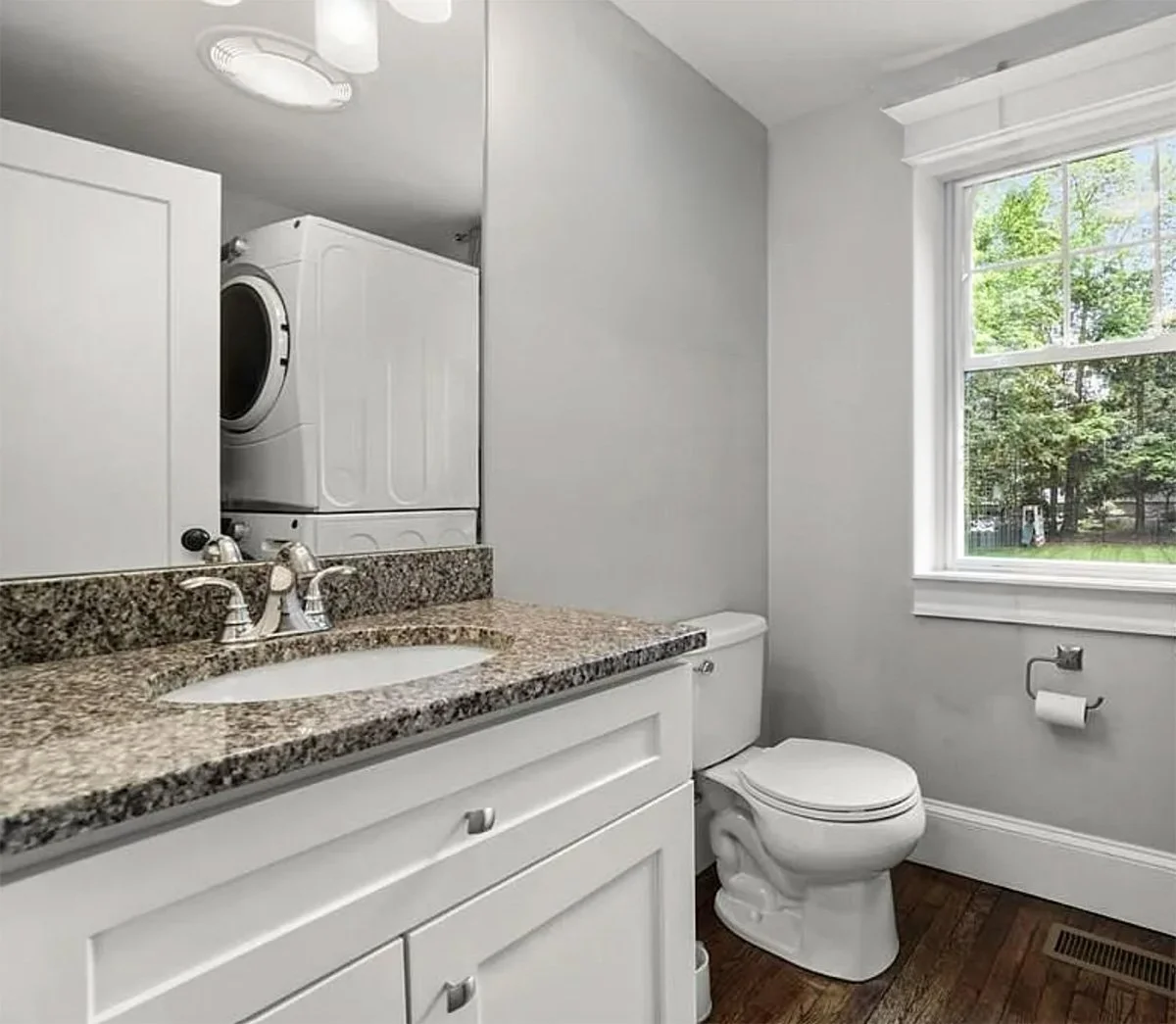 Existing cramped powder room showing reflection of stacked laundry