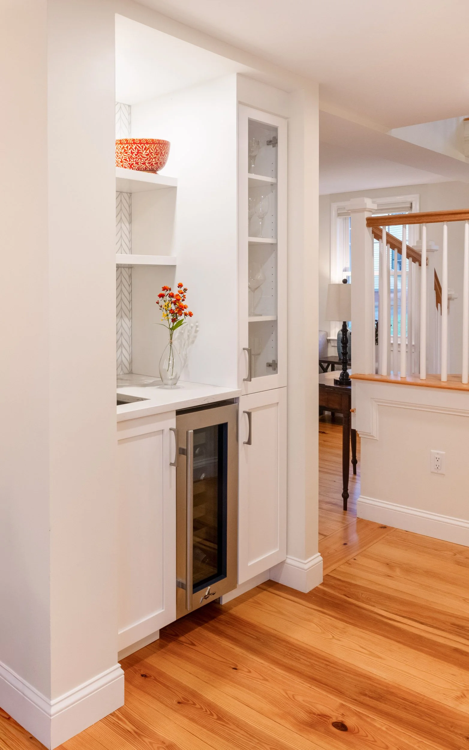 A wet bar with glass shelving and a wine refrigerator.