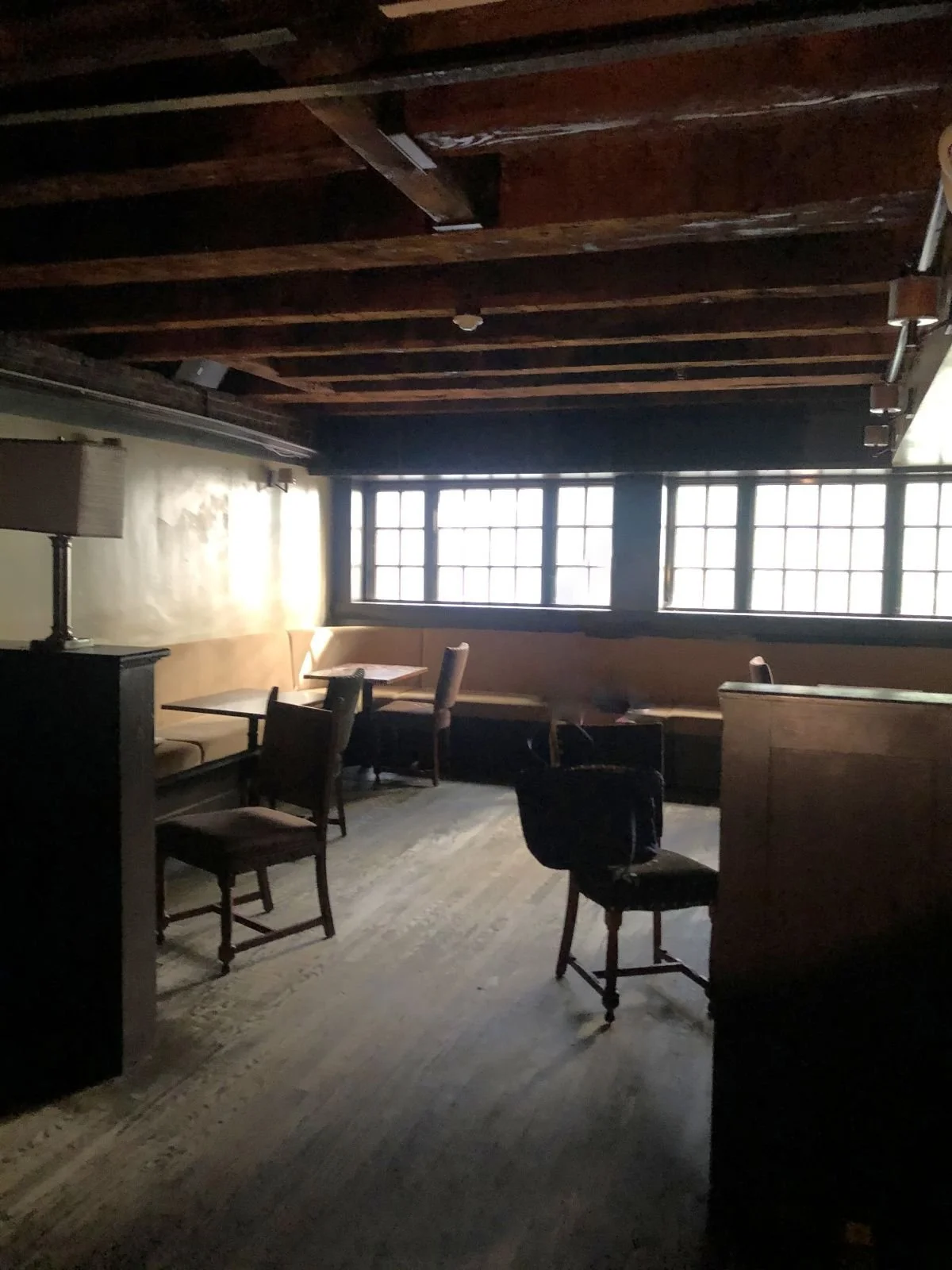 A former dining room with wood-framed windows and mismatched chairs.