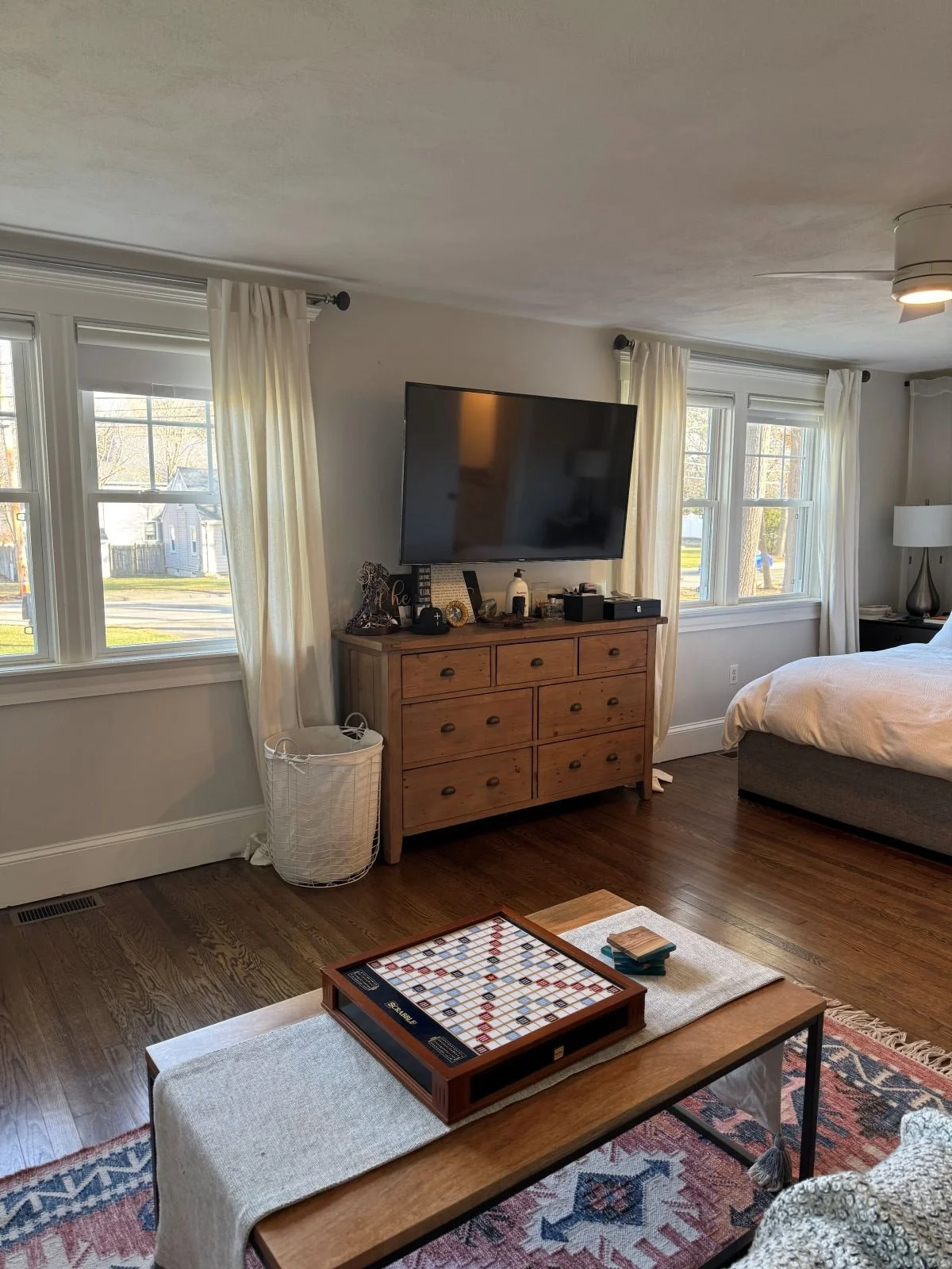 Existing ground level primary bedroom of a Dutch Colonial home in Greater Boston prior to second story addition showing original layout, dresser and north facing windows before renovation by Tact and Grit Design Co.