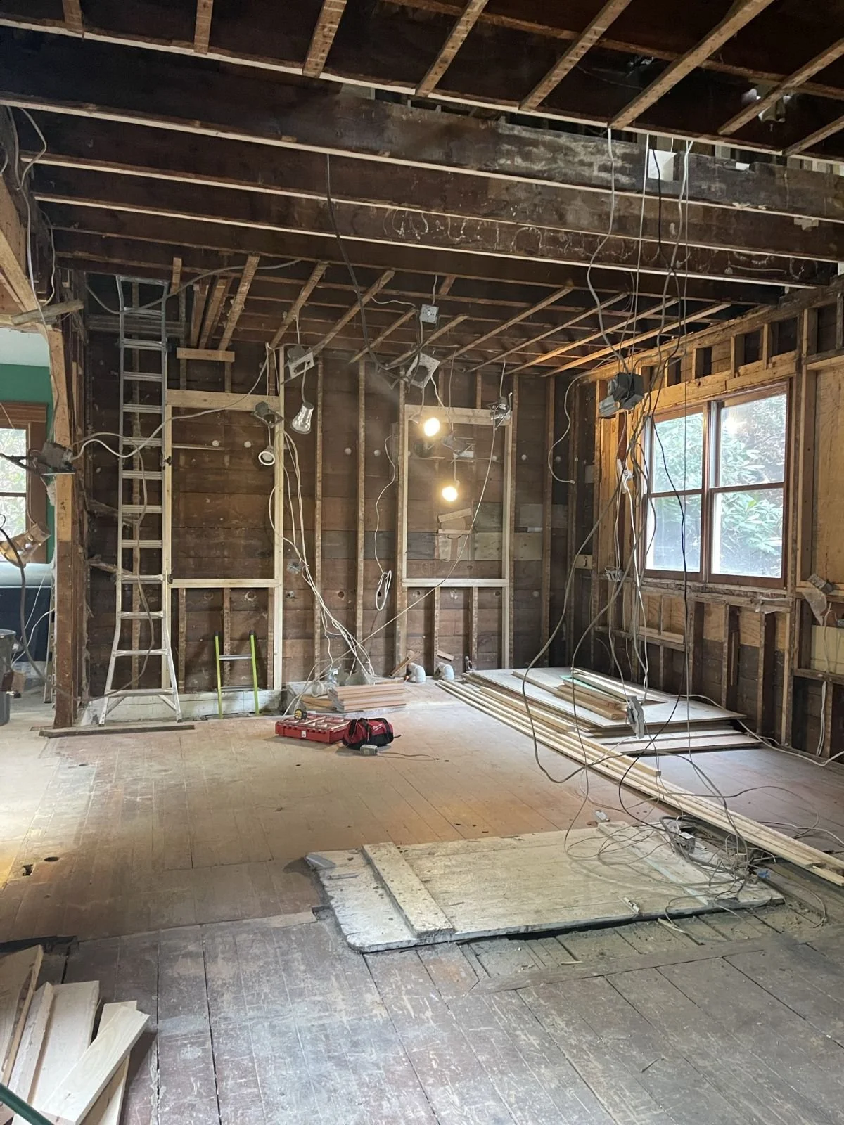Interior view of the demolition phase in a historic home, showing exposed wall studs and the diagnostic screening of existing structural elements.