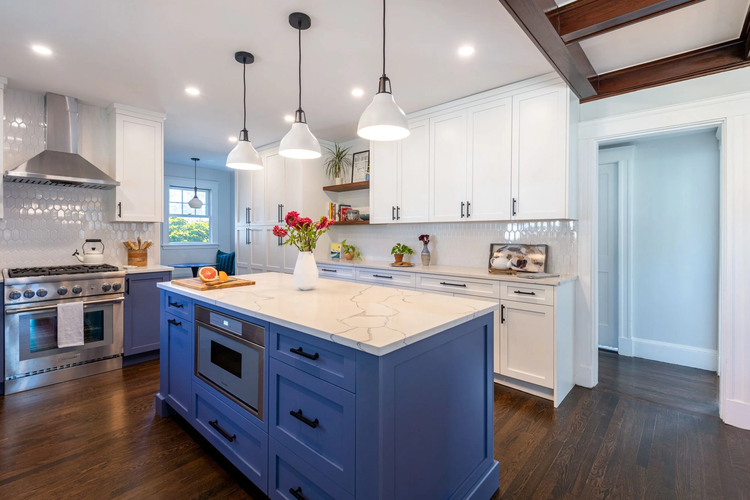 Kitchen island with integrated Thermador range and white pendant lights above in Medford, MA kitchen.