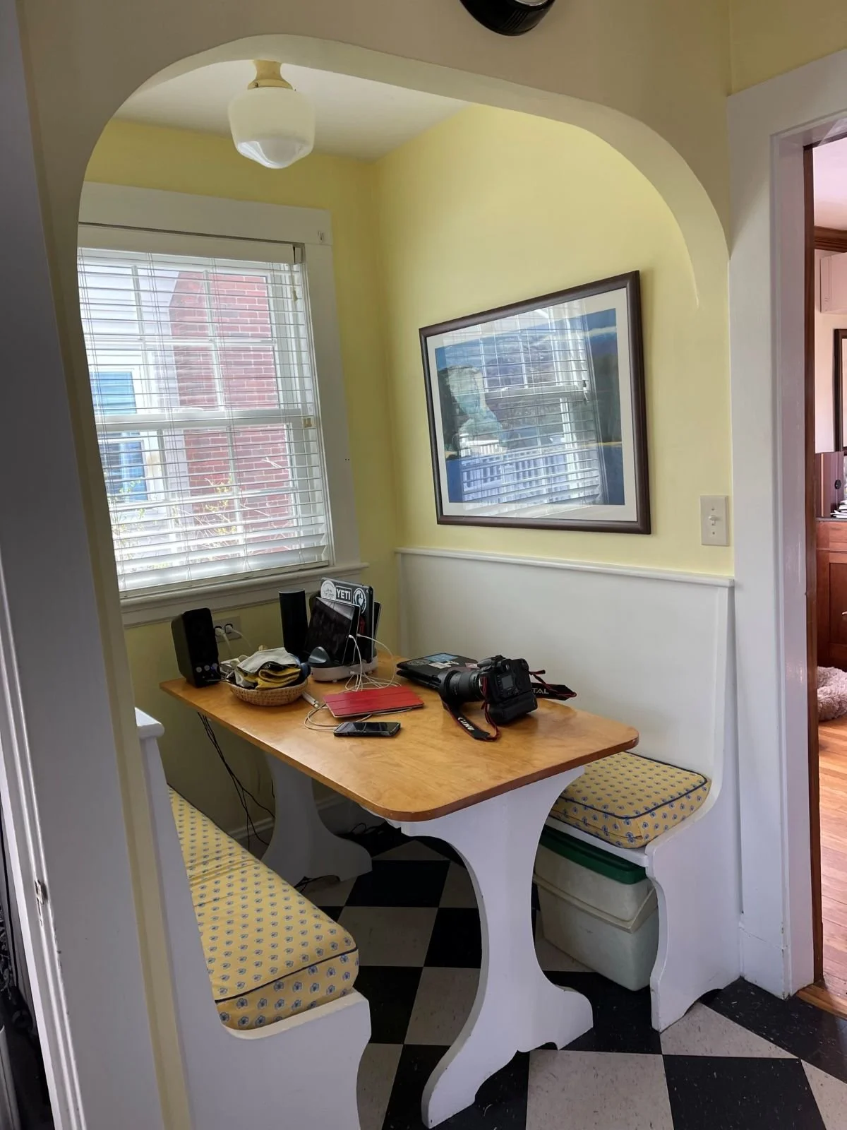 Existing two-toned yellow and white breakfast nook with built-in benches and wood topped table