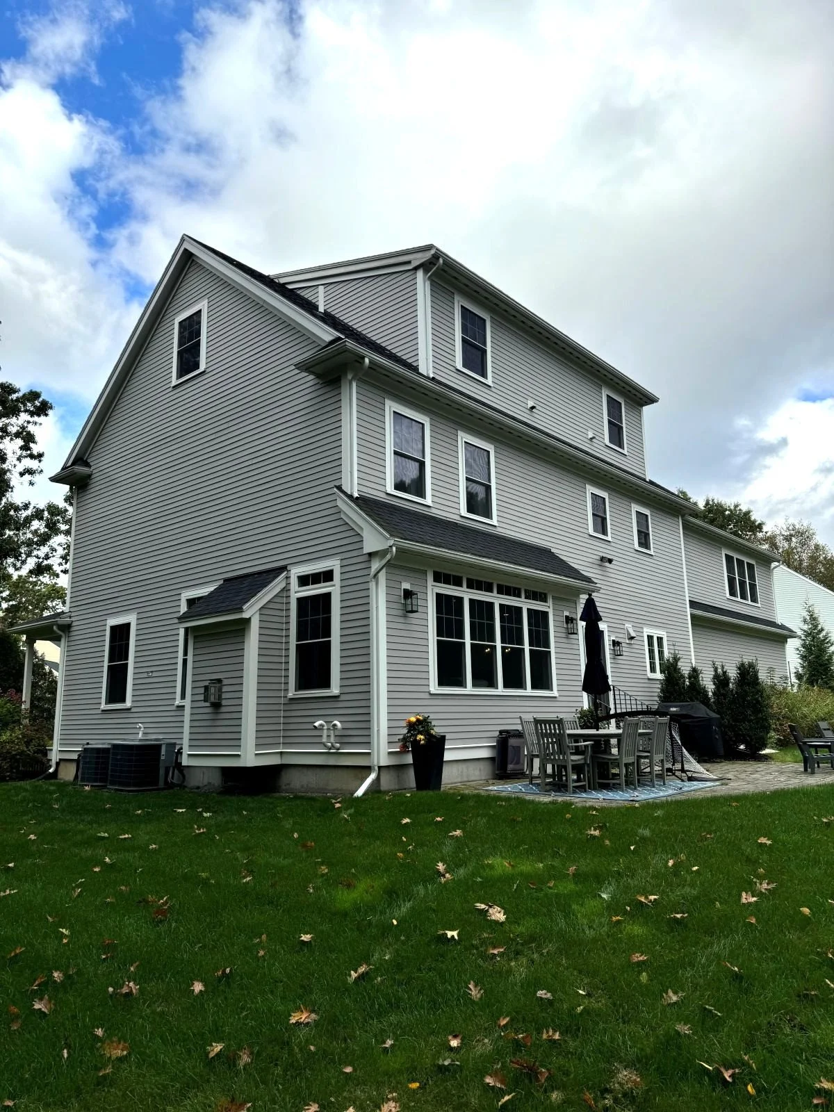 The rear corner of a Hamilton MA home showing the existing patio and mechanical equipment before renovation.
