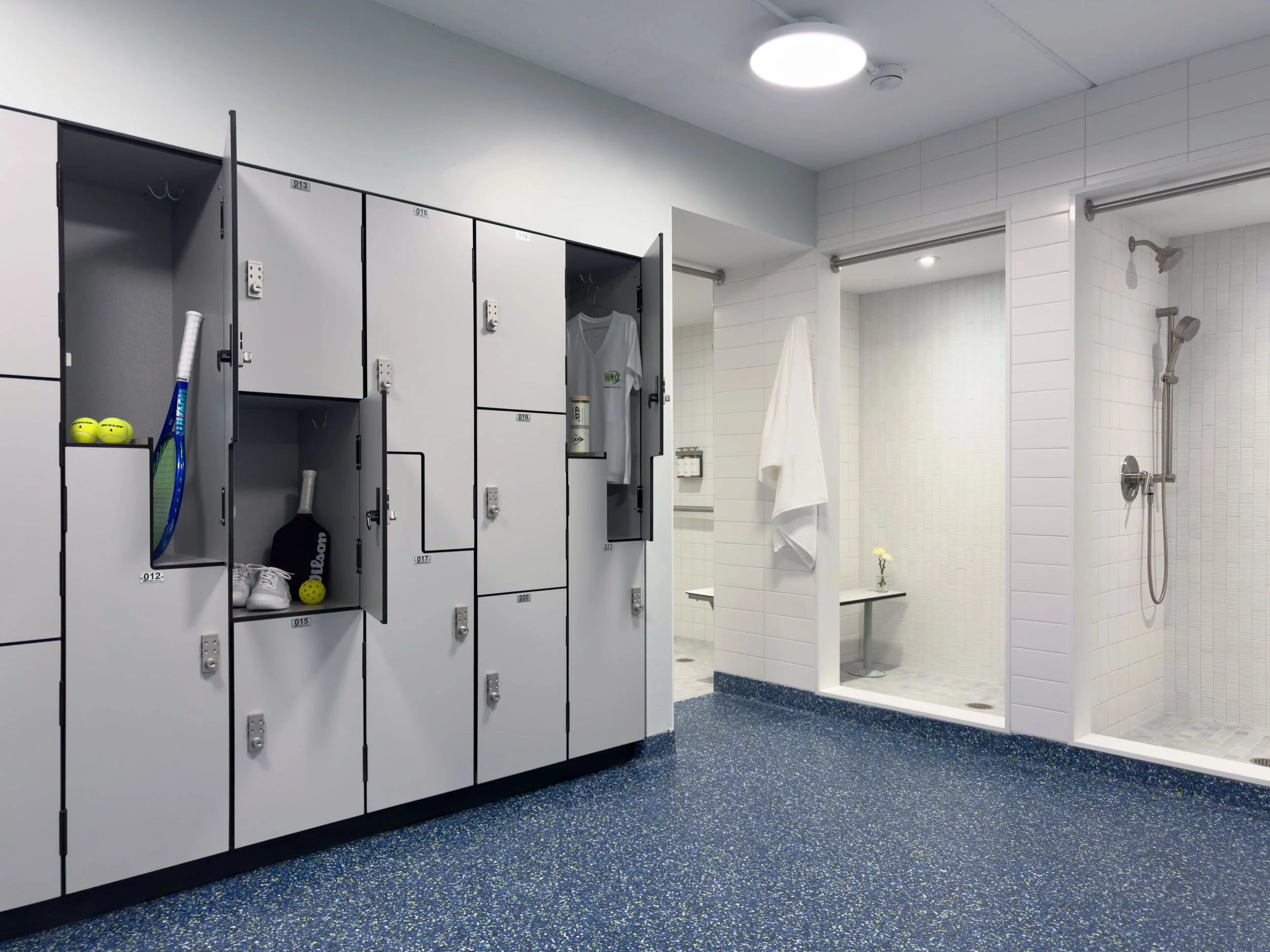 grey built-in locker system with integrated lock in a locker room with epoxy flooring and  shower stalls