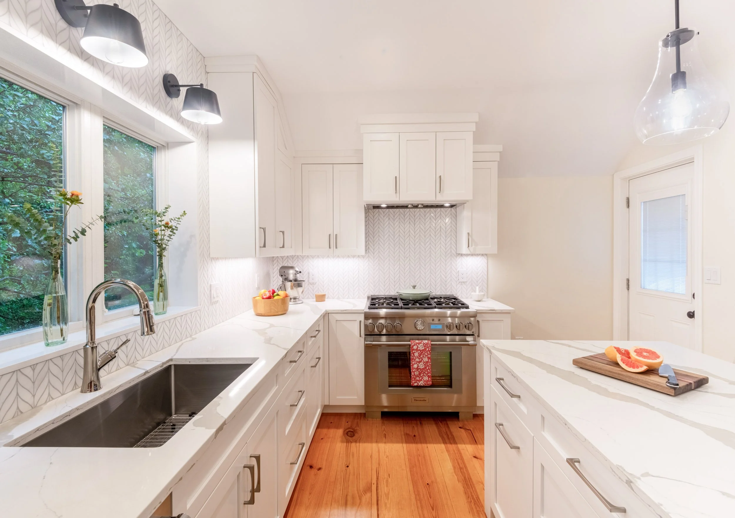 A kitchen with undermount stainless sink and sightline to Thermador range and custom hood.