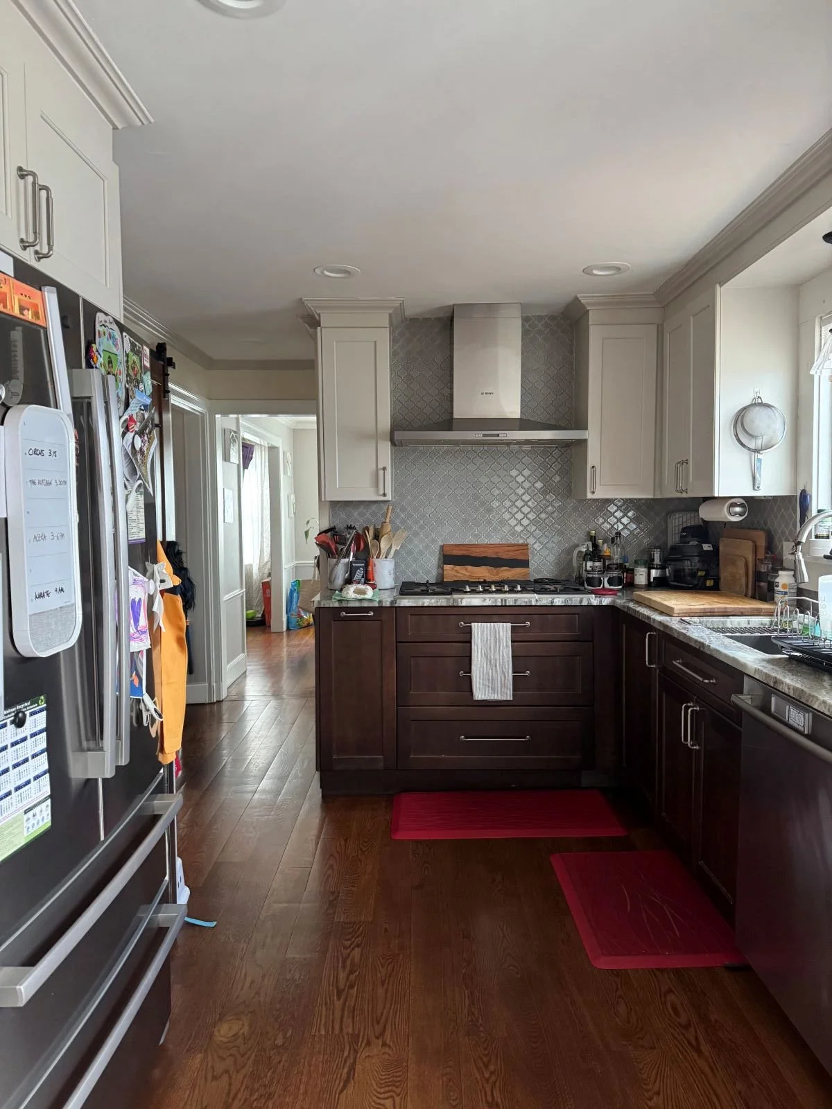 Existing kitchen interior of a colonial home in Melrose MA prior to addition showing two tone cabinetry, patterned tile backsplash, and limited counter space before renovation.