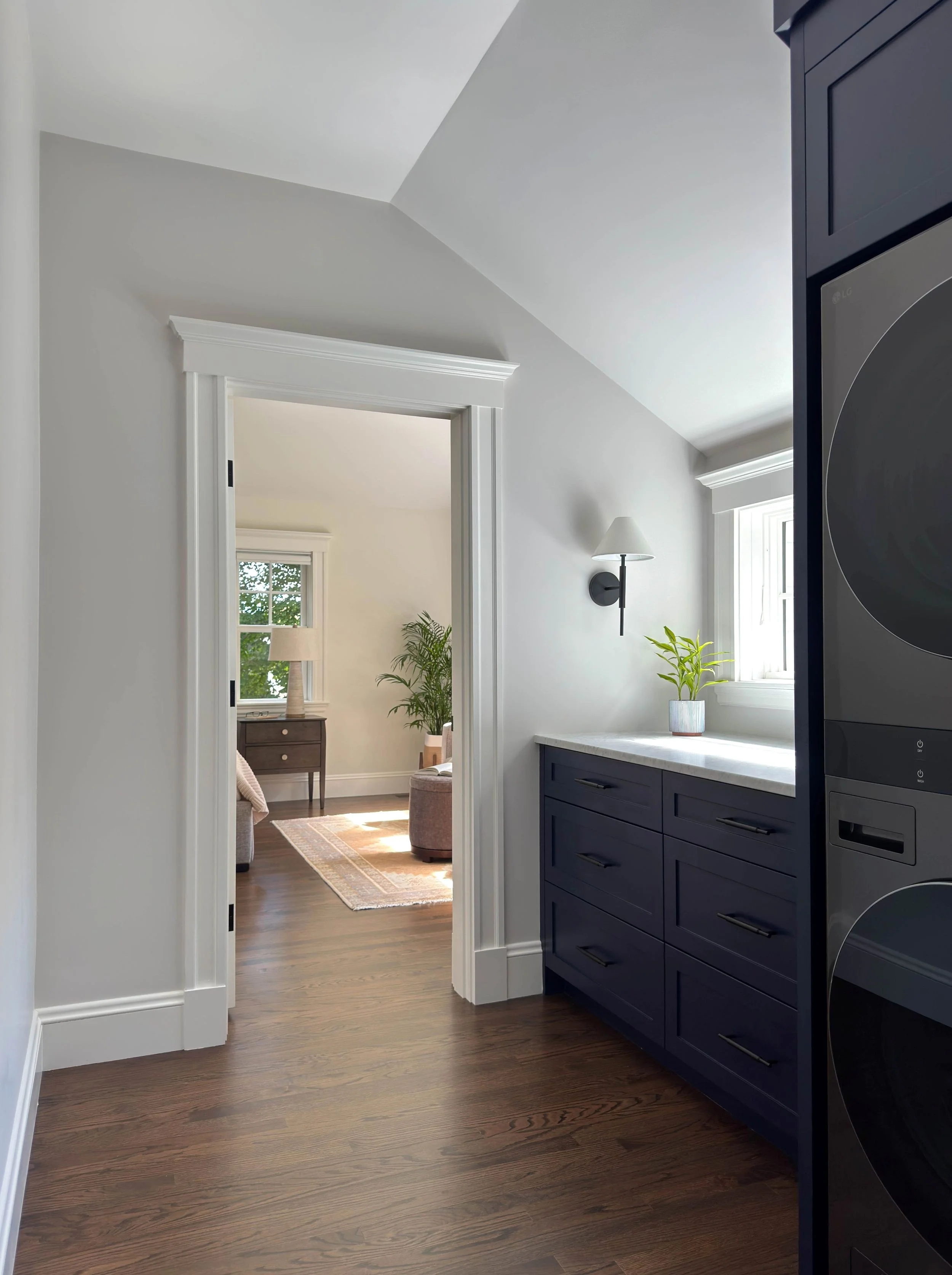 primary suite entry foyer with custom laundry station with marble folding counter and integrated washer and dryer with views into bedroom