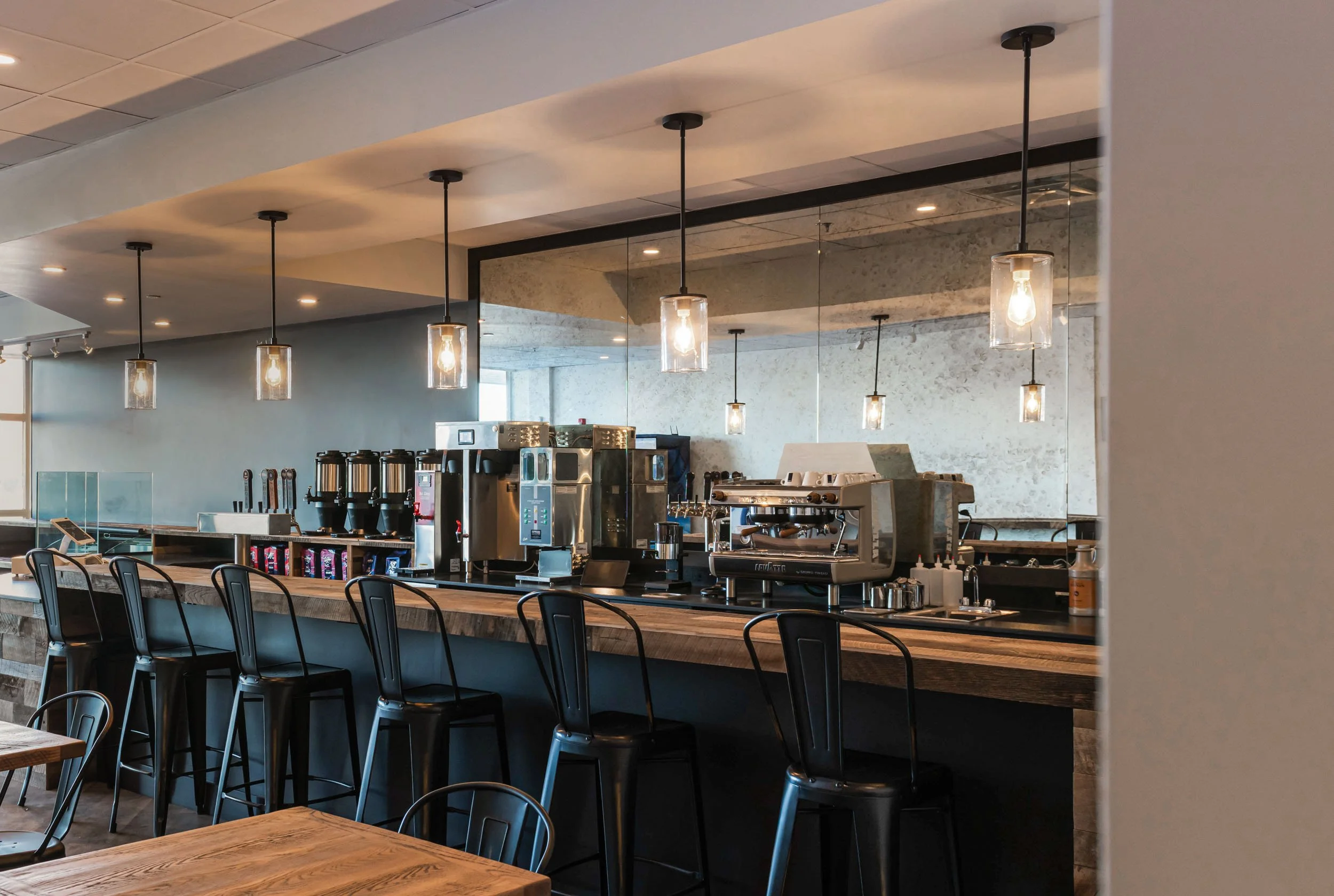 coffee shop fit out featuring custom coffee bar with glass pendant lights and antique mirrored glass behind coffee equipment