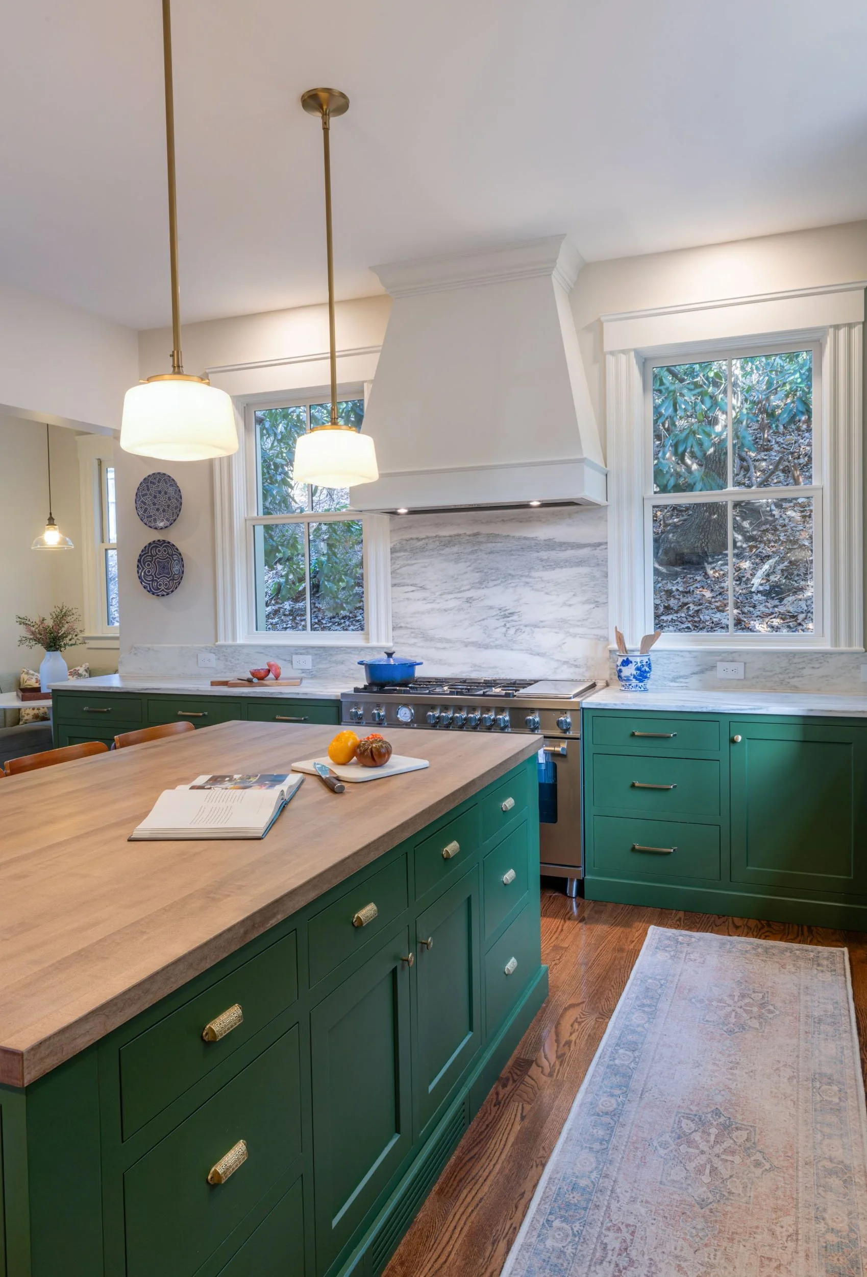 Renovated kitchen in an 1846 Victorian home in Newton, MA showing working side of island with butcher block top viewed towards custom white range hood