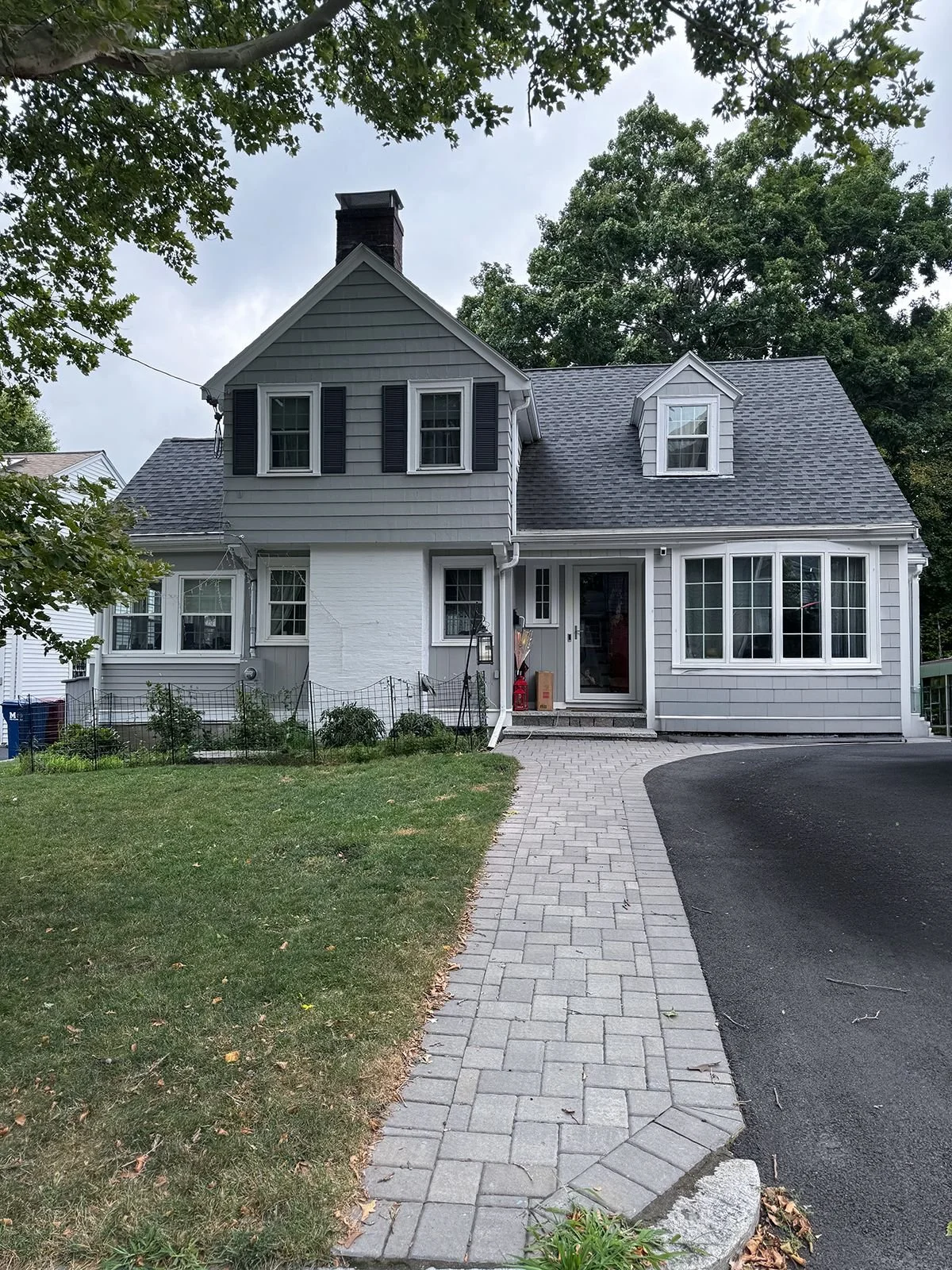 Existing front facade of a cape style home in Melrose MA prior to porch addition and rear kitchen addition showing original entry and street presence before renovation.