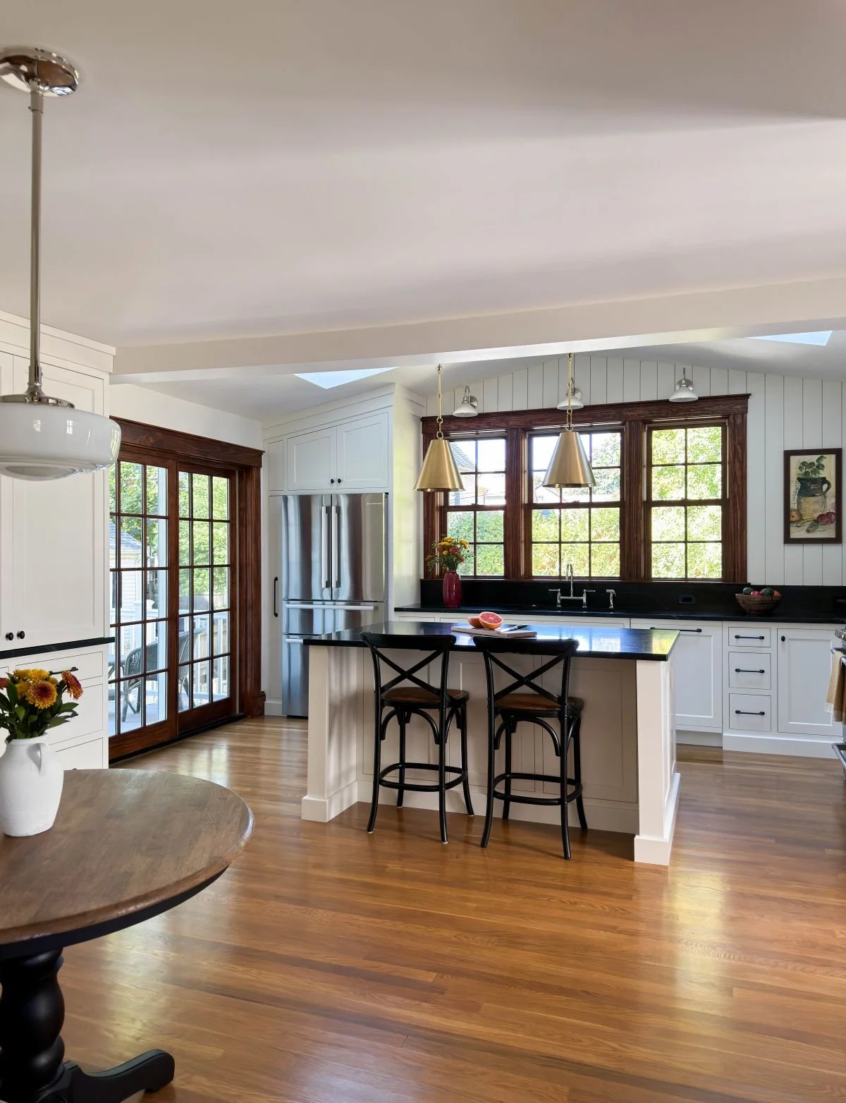 Reimagined Dutch Colonial kitchen and breakfast nook in Medford, MA, featuring deep soapstone countertops, stained wood trim that honors the home’s original character, and a sun-filled open layout.