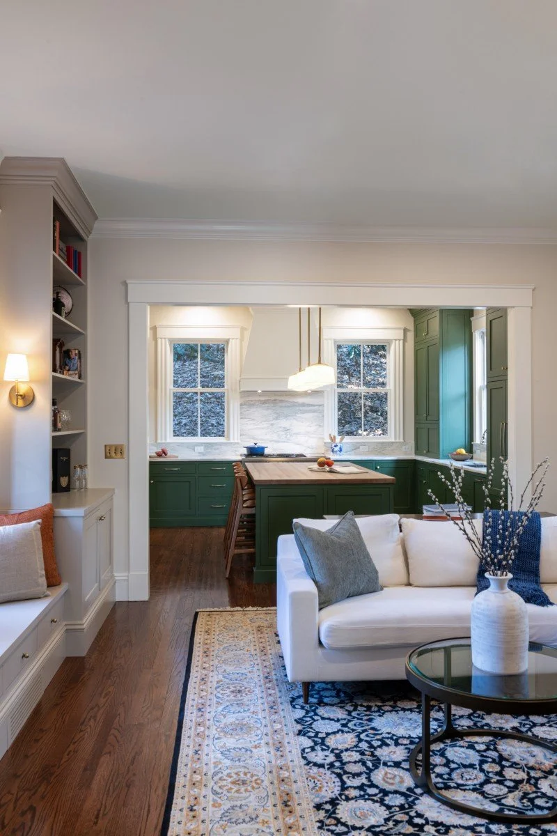 The completed open-concept kitchen featuring custom green cabinetry, marble surfaces, and a seamless transition to the living area.