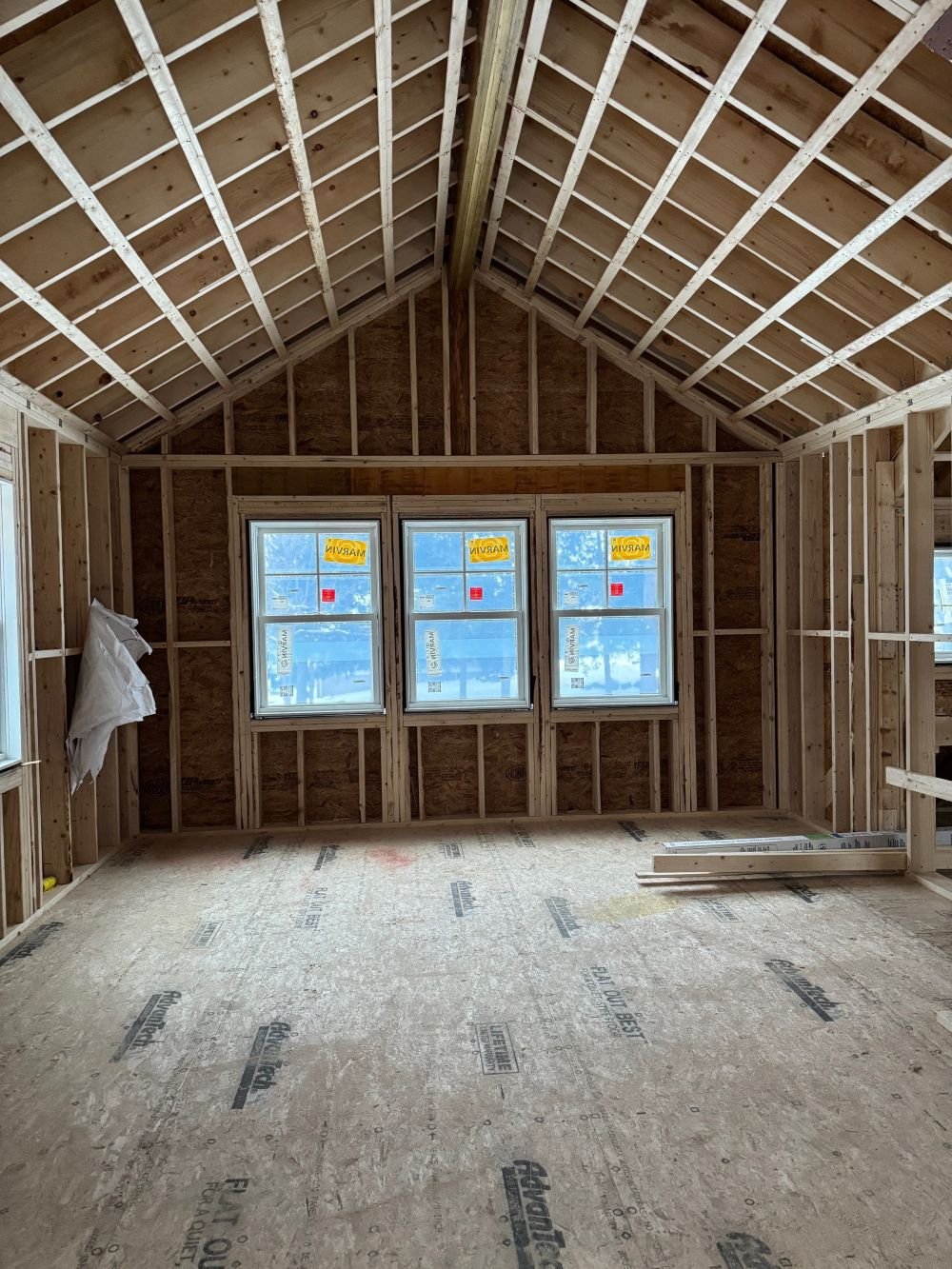Second level interior framing phase of a Dutch Colonial second story addition in Greater Boston showing vaulted ceiling framing and new window openings designed by Tact and Grit Design Co.