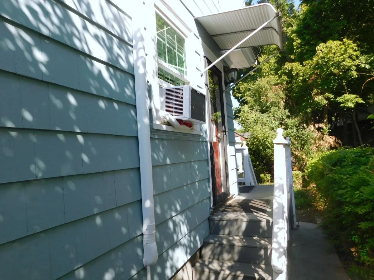 Existing side entry of Dutch Colonial home in Medford MA before kitchen addition, showing original siding and walkway