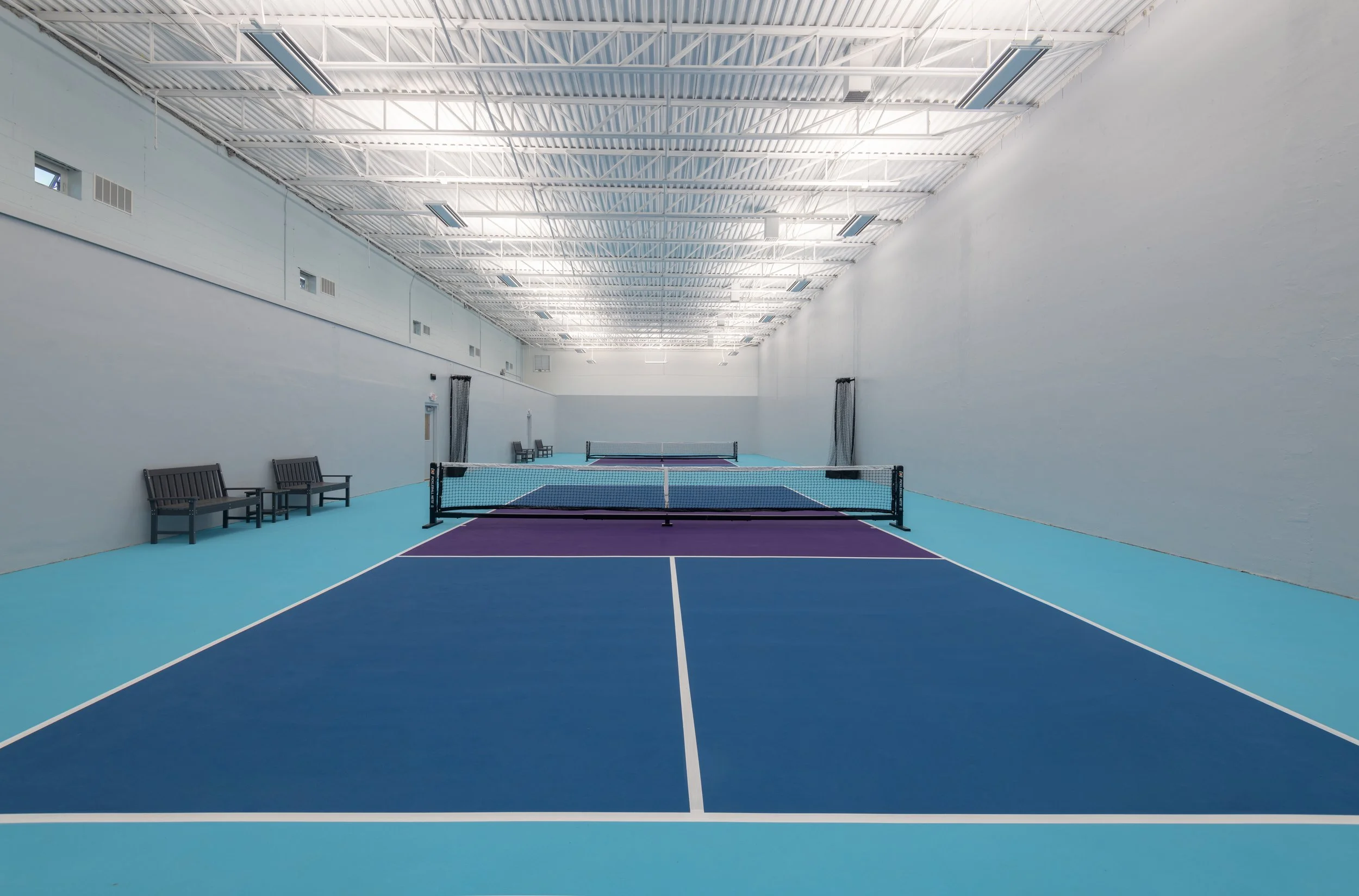 A view of two new indoor pickleball courts at Woburn Racquet Club, converted from old racquetball courts through cinderblock partition removal and floor reconfiguration.