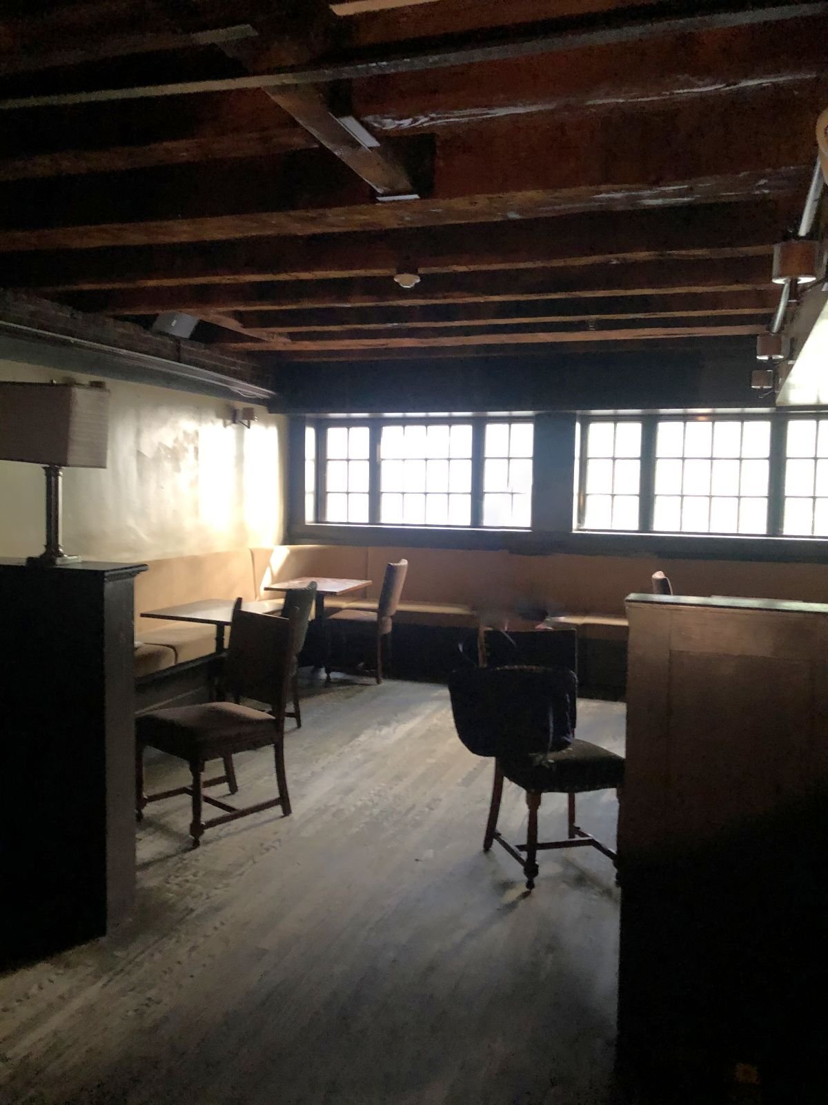 A former dining room with wood-framed windows and mismatched chairs.