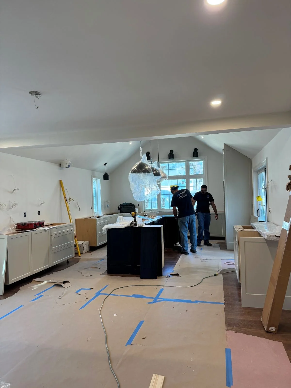 Installation of the custom cabinetry and the 10-foot black stained oak island within the vaulted kitchen addition.