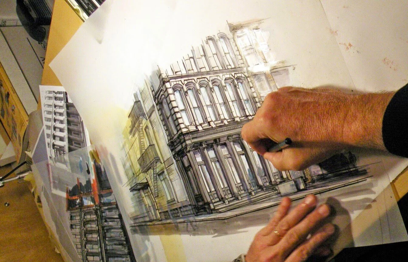 A person drawing a detailed architectural illustration of a multi-story building on a large sheet of paper, with colored pencils or markers nearby.