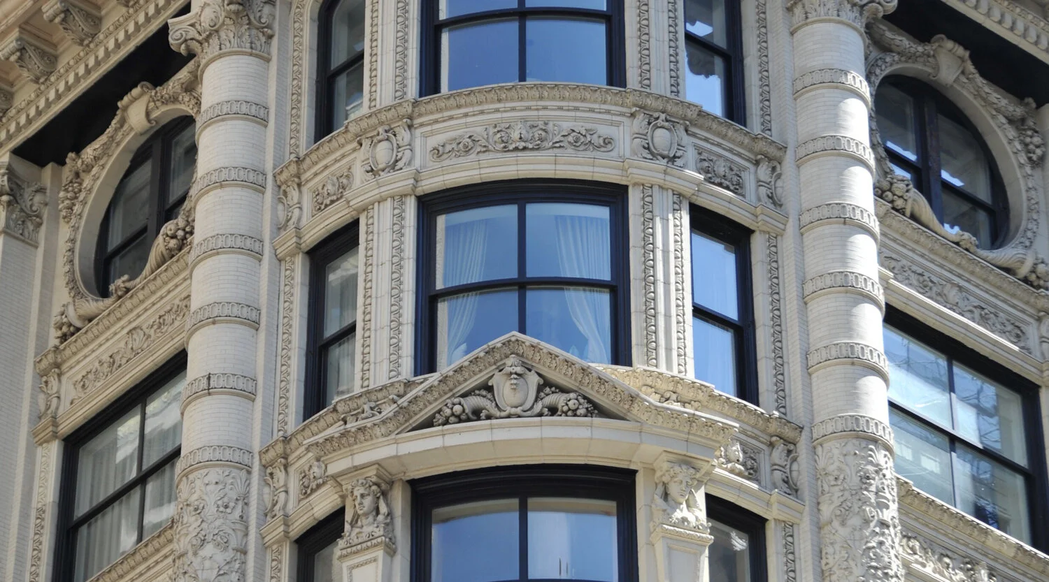 Close-up of an ornate historic building facade with detailed stonework, decorative reliefs, and large windows.