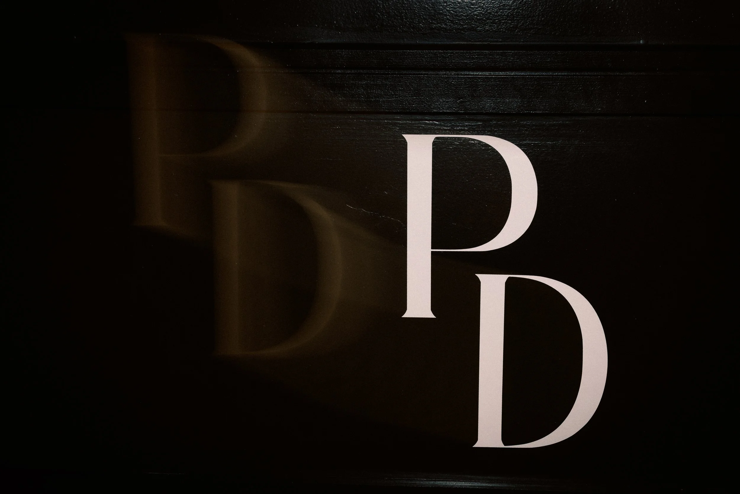 Large white letters 'P' and 'D' on a black background with a faint yellow reflection.
