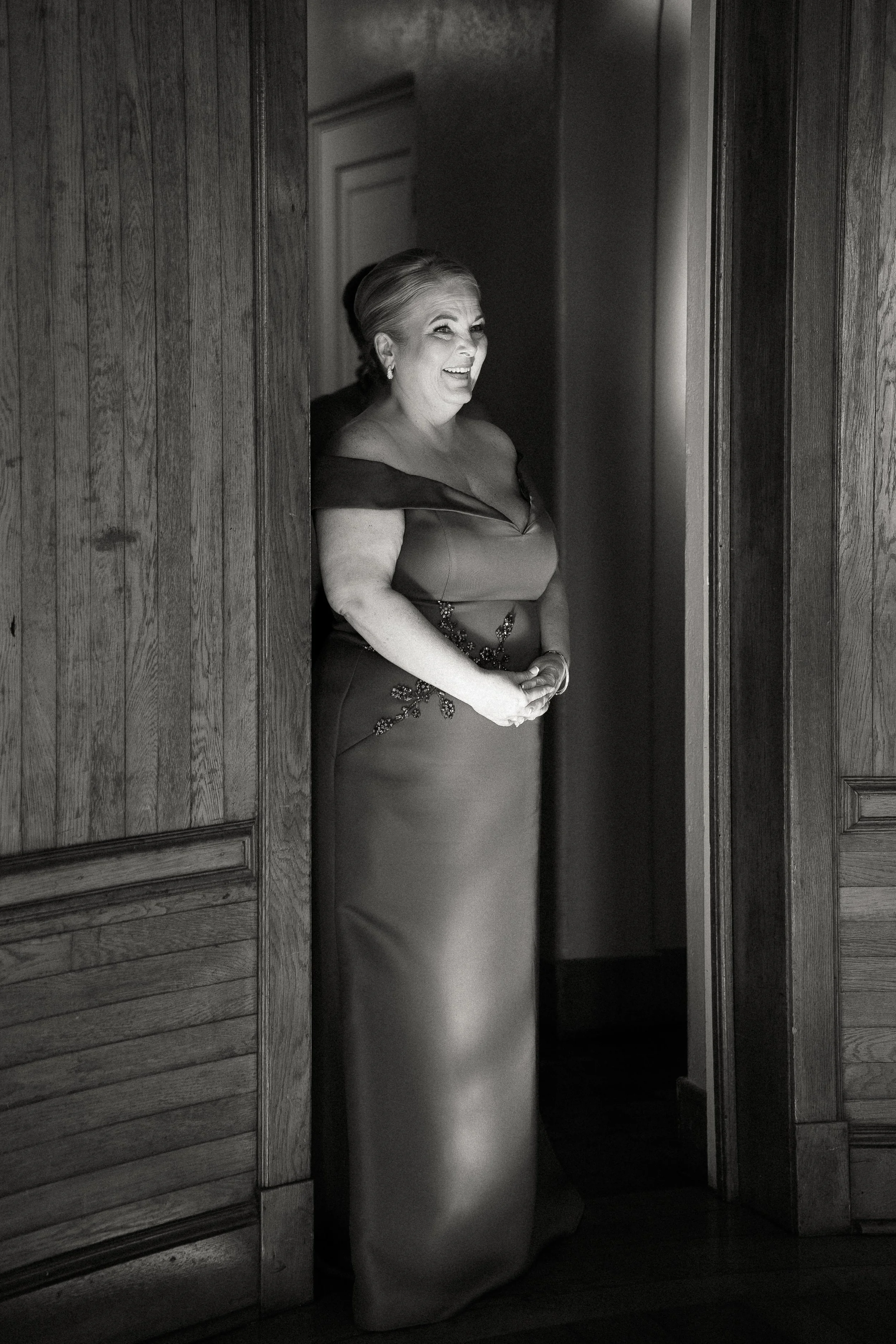 A woman in an elegant gown standing in a doorway, smiling.