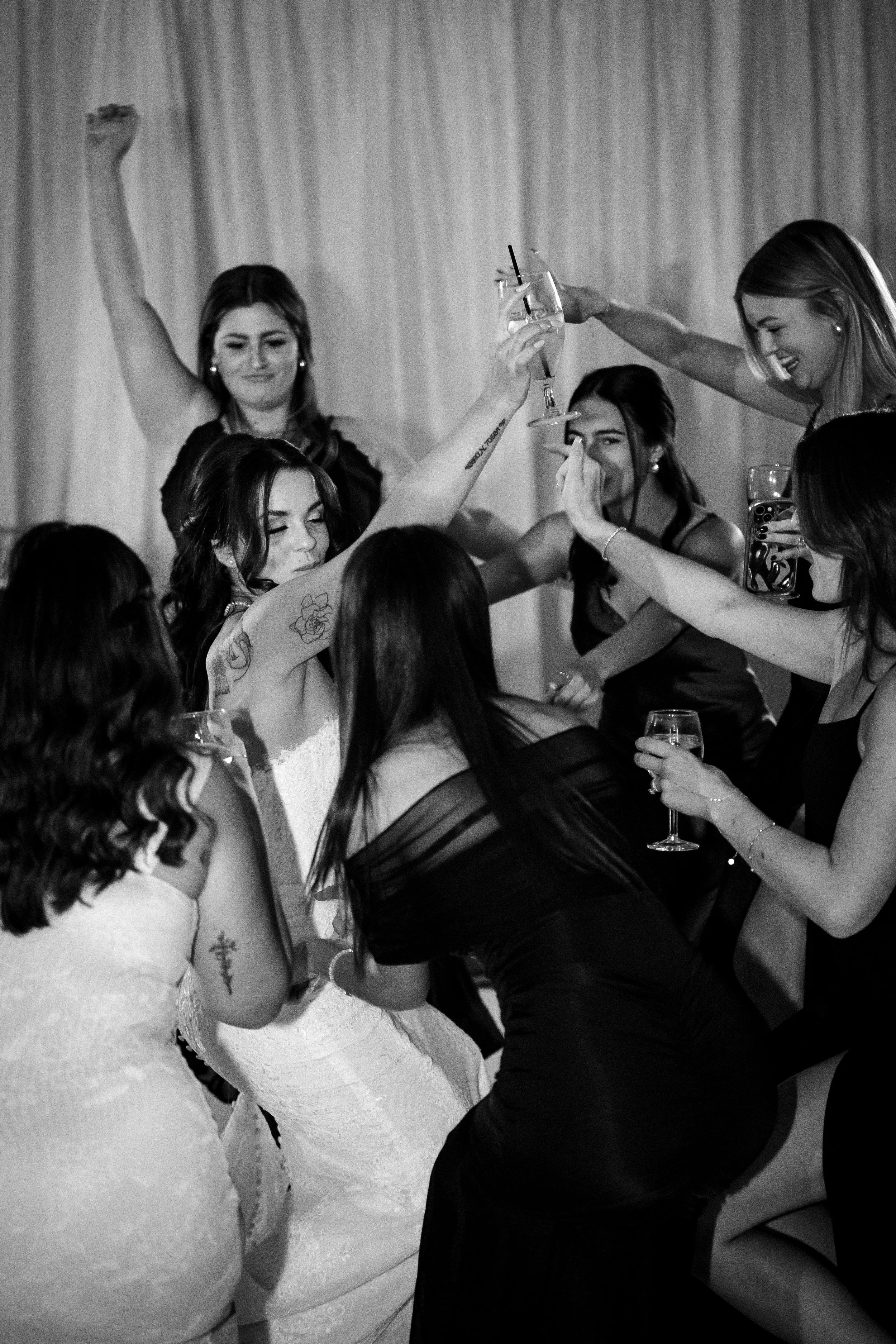 Group of women celebrating at a party, raising glasses in a toast, smiling and having fun.