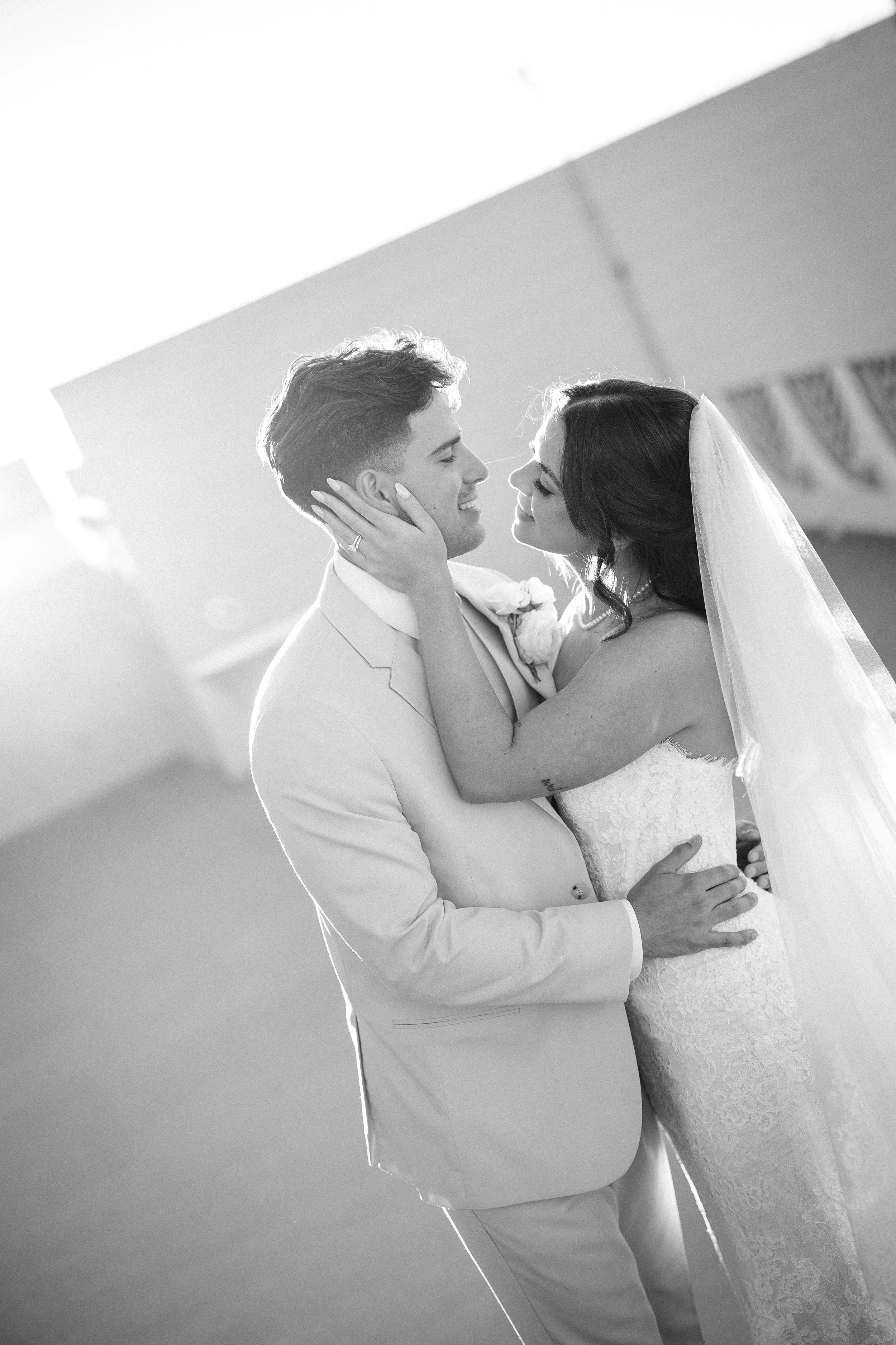 Black and white photo of a bride and groom embracing on their wedding day outdoors.