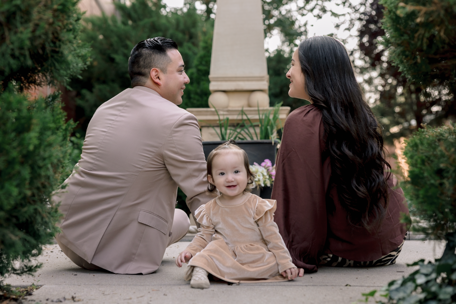 Two children playing near the edge of a lake during sunset, with trees in the background and the sun reflecting on the water.
