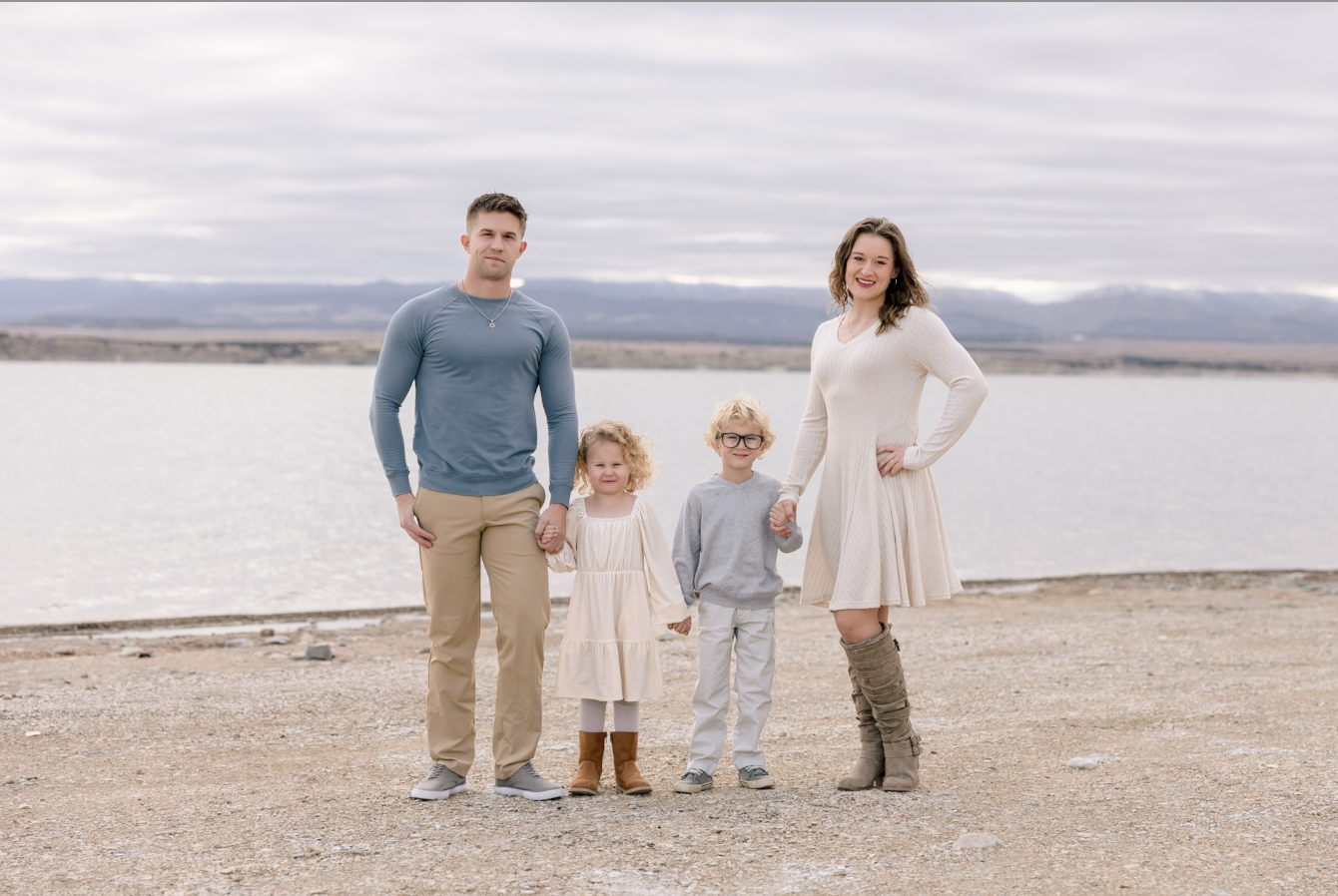 Black and white photo of a man and woman standing outdoors among trees, facing opposite directions with serious expressions, the woman in the foreground and the man slightly behind.