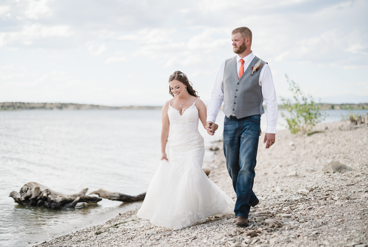 Young man sitting outdoors on grass near a tree, wearing a colorful floral shirt and blue jeans, with a thoughtful expression.