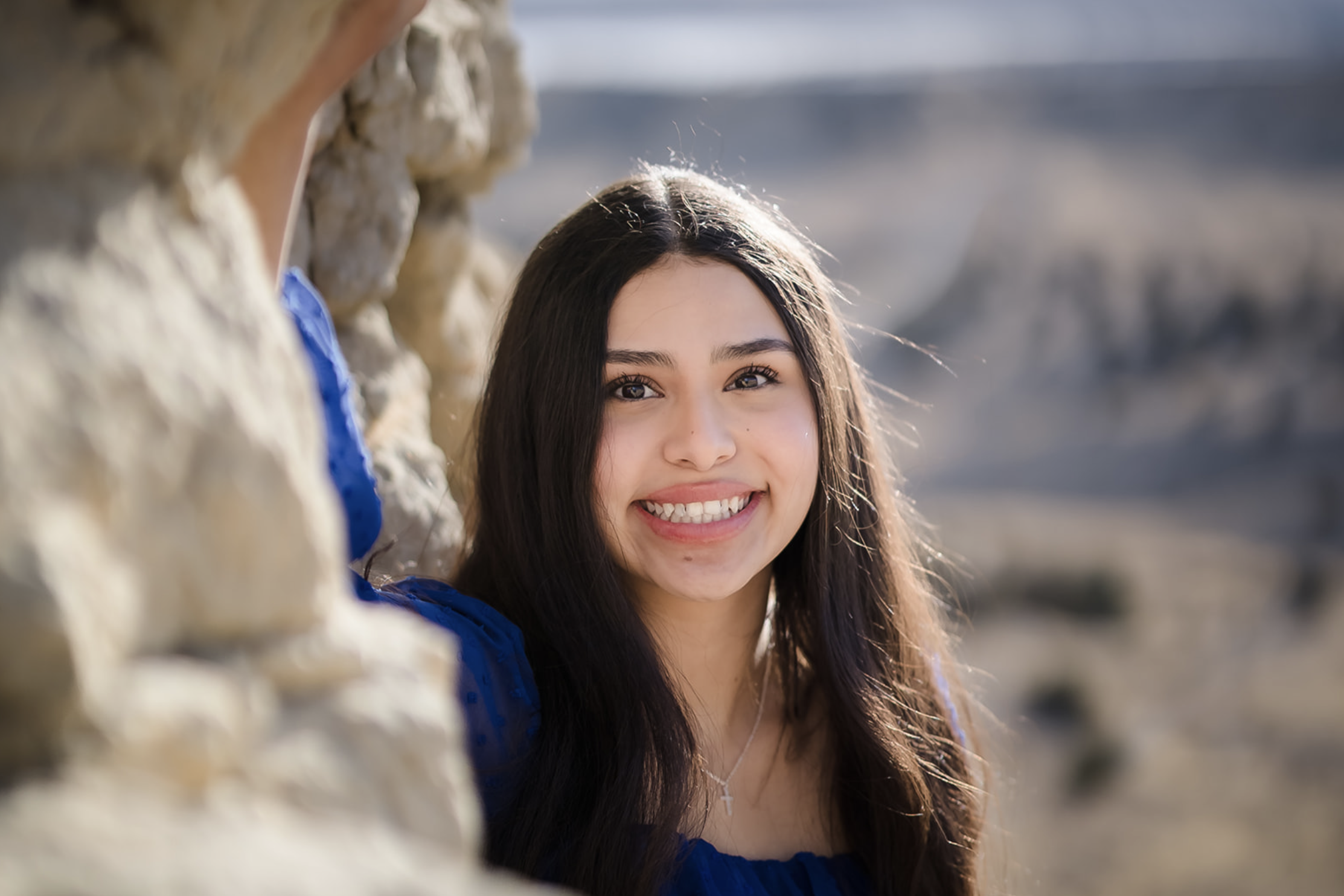 Black and white photo of a man and woman standing outdoors among trees, facing opposite directions with serious expressions, the woman in the foreground and the man slightly behind.