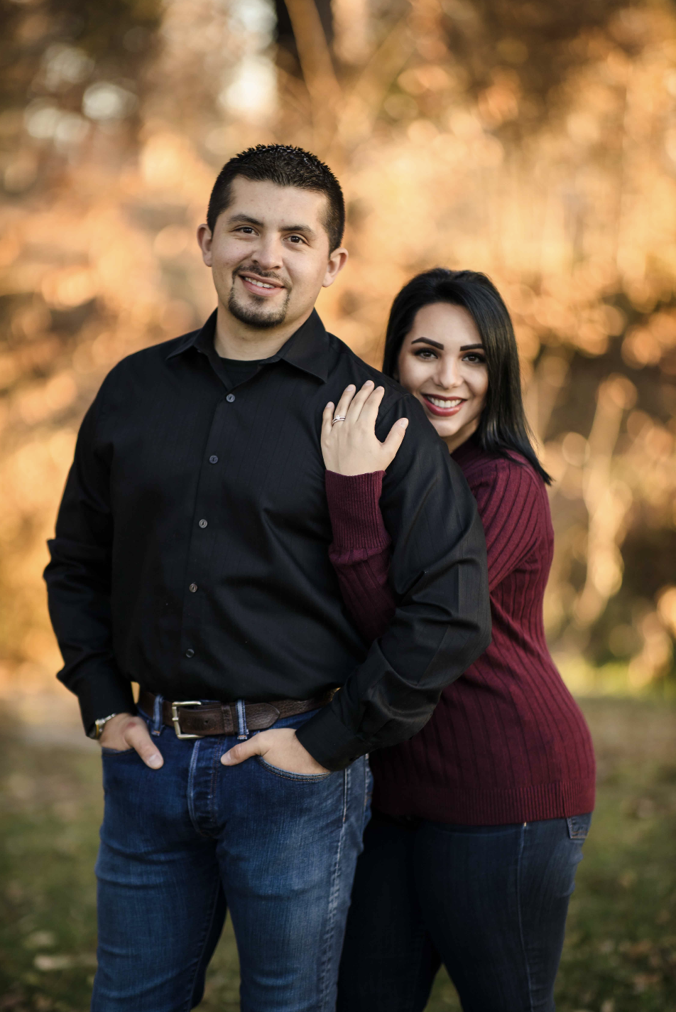 Two children playing near the edge of a lake during sunset, with trees in the background and the sun reflecting on the water.