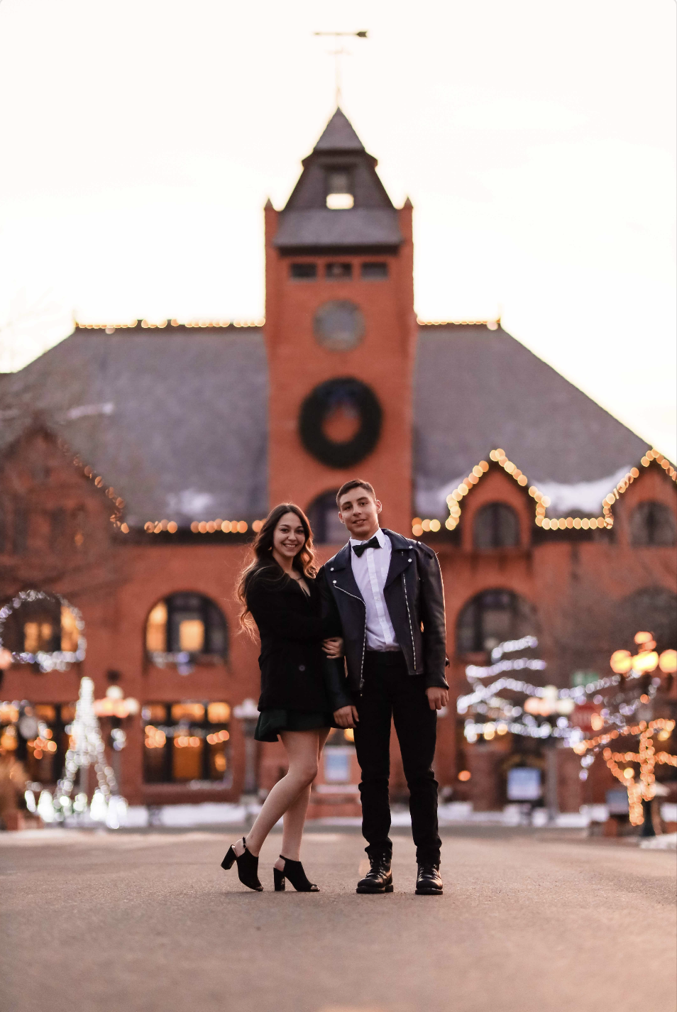Black and white photo of a man and woman standing outdoors among trees, facing opposite directions with serious expressions, the woman in the foreground and the man slightly behind.