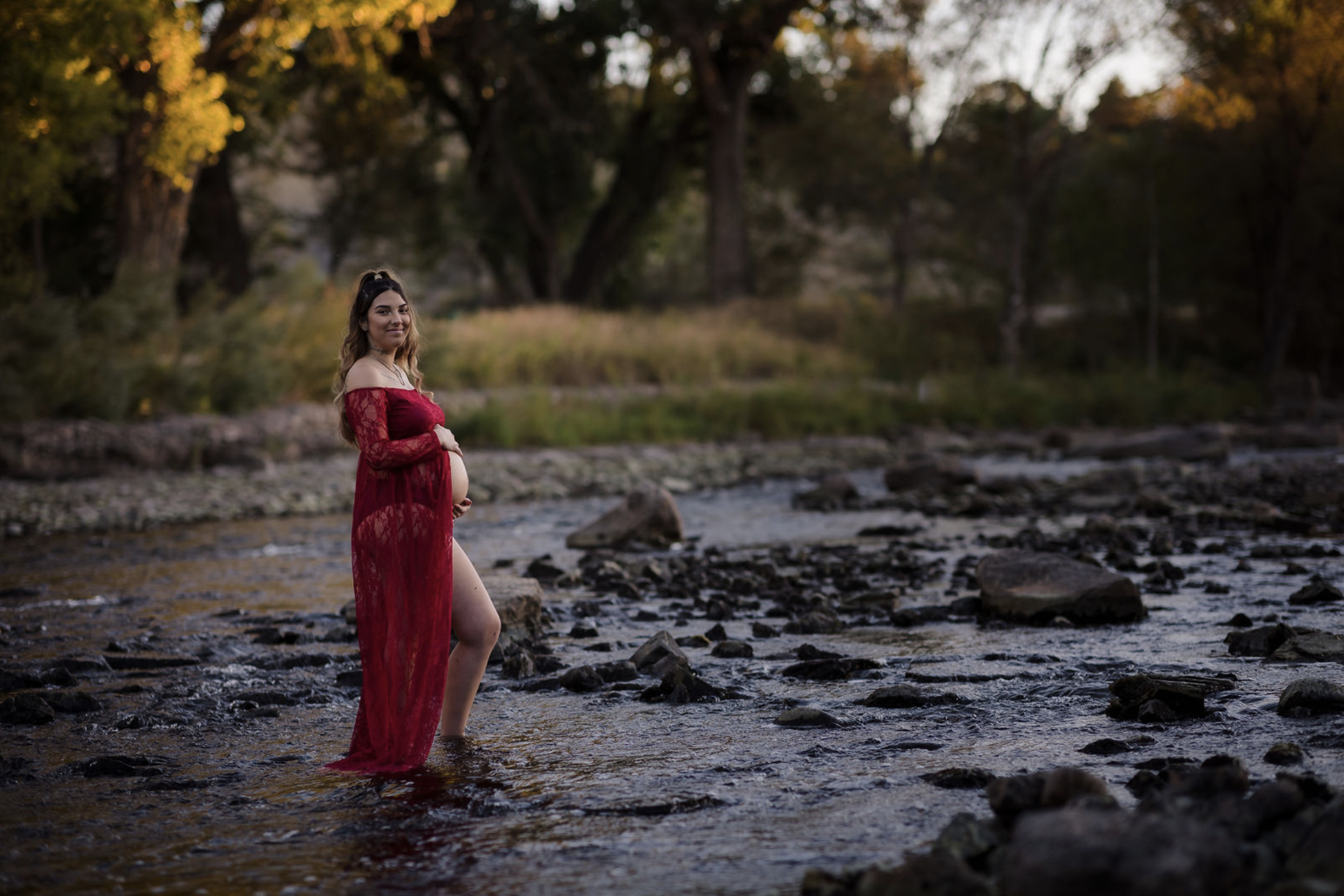 Black and white photo of a man and woman standing outdoors among trees, facing opposite directions with serious expressions, the woman in the foreground and the man slightly behind.