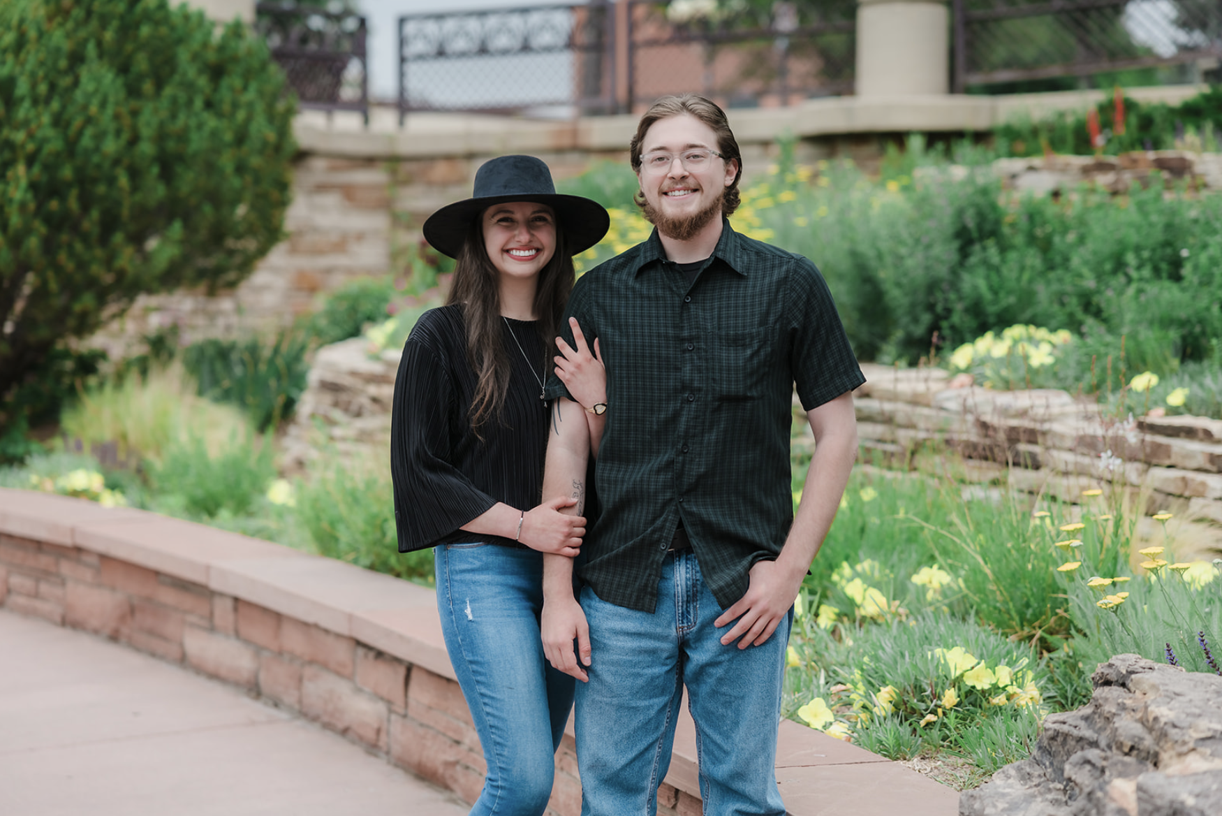 Two children playing near the edge of a lake during sunset, with trees in the background and the sun reflecting on the water.