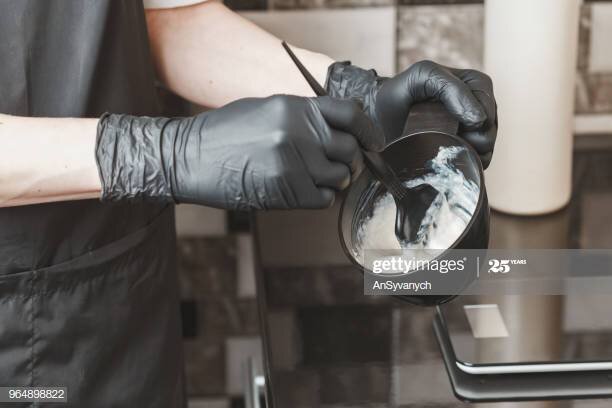 Stylist preparing a hair dye in a container, hairdresser salon concept