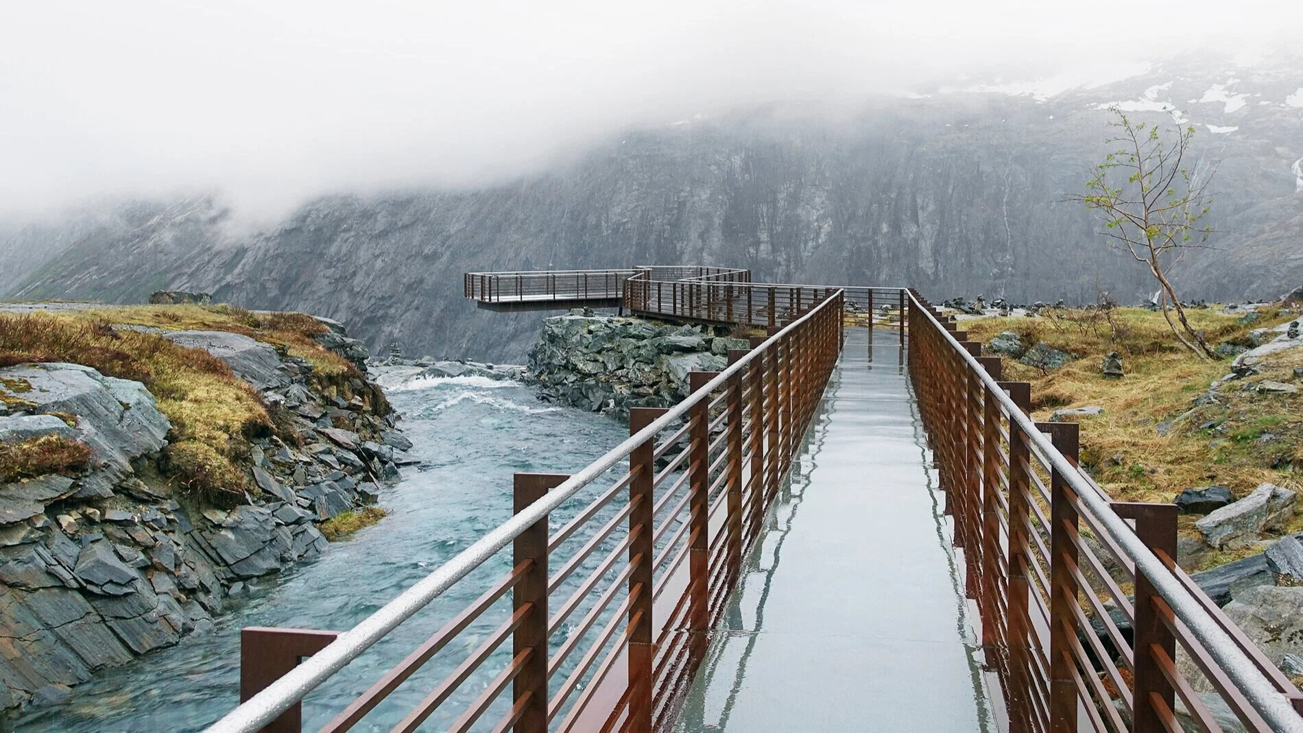 Stålet og betongen skinner i det våte været og man ledes ut til kanten av stupet.