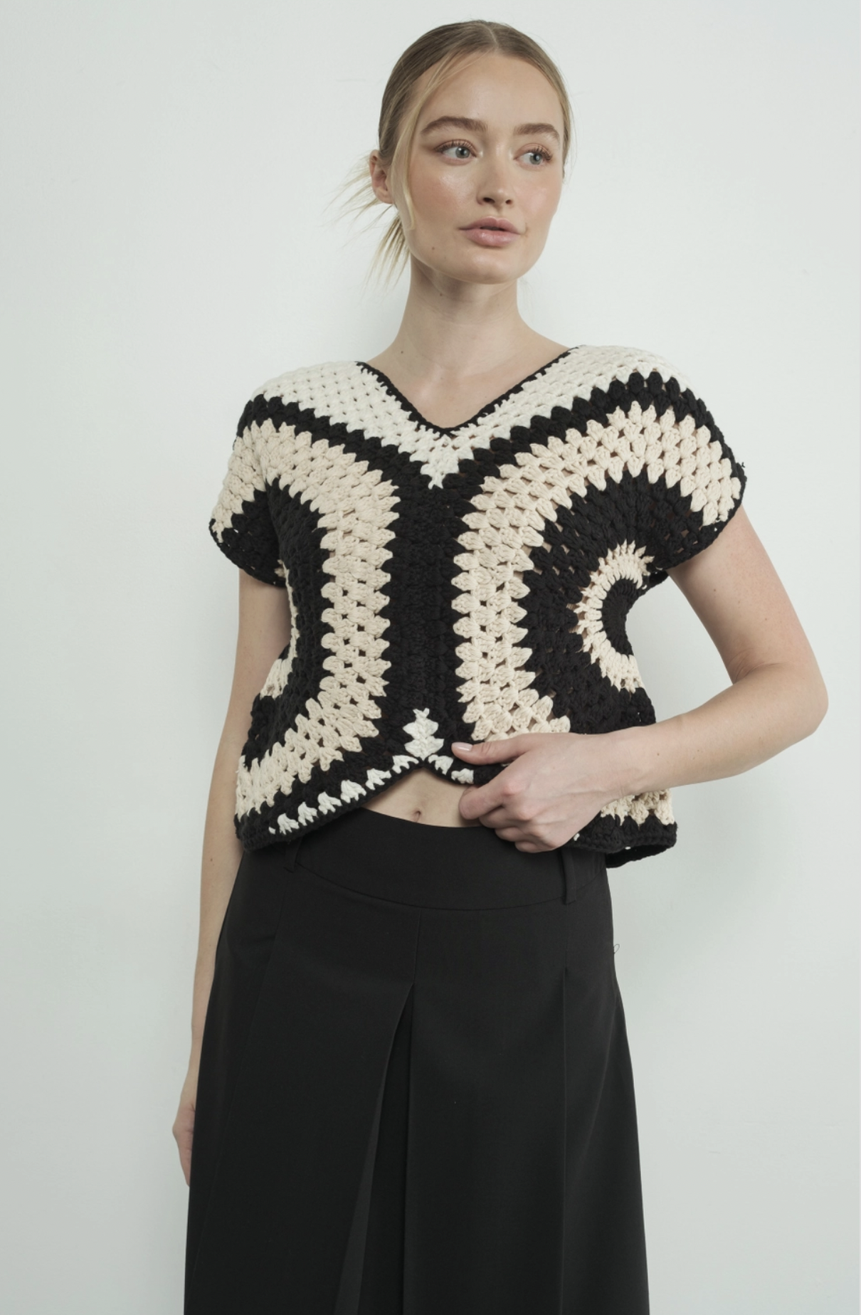 Model wearing the cream black and white crocheted sweater top