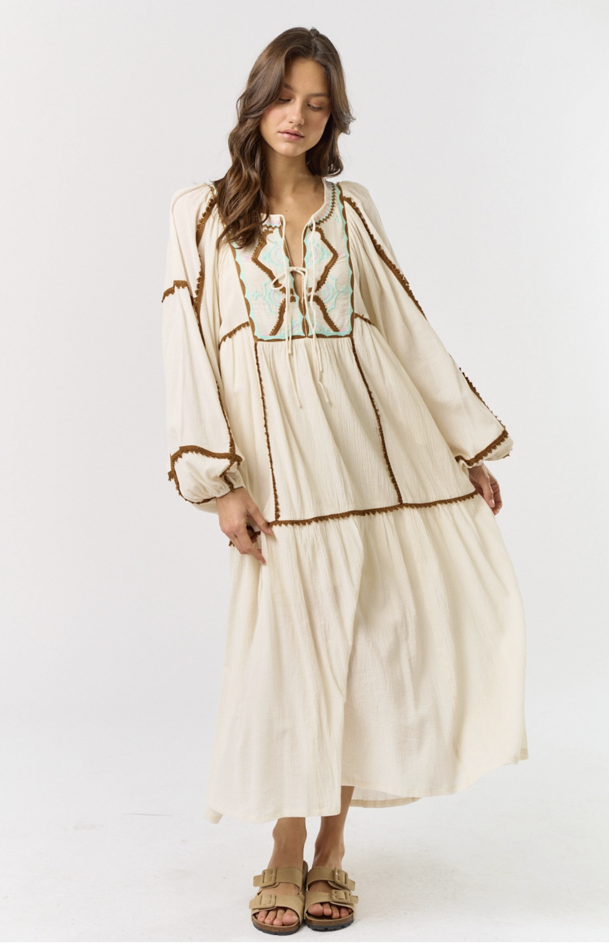 Model wearing a long flowing white embroidered bohemian dress
